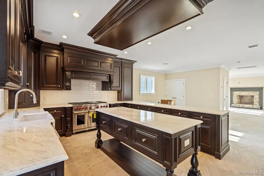 Kitchen with dark brown cabinetry, a peninsula, open floor plan, double oven range, and crown molding Kitchen with dark brown cabinetry, a peninsula, open floor plan, double oven range, and crown molding