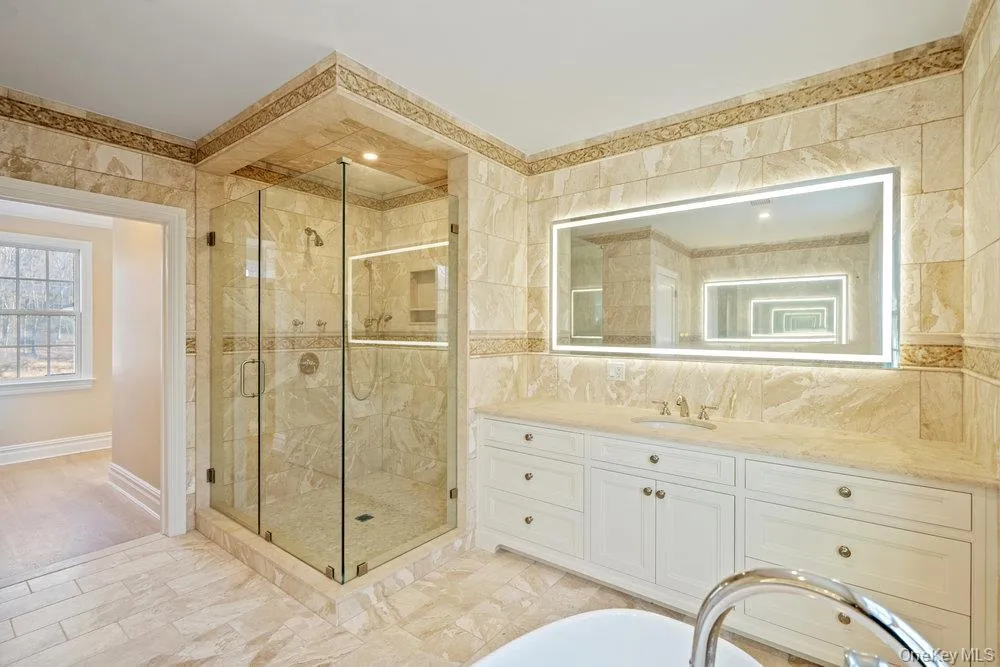 Bathroom with vanity, tile walls, a shower stall, light marble finish floors, and a soaking tub Bathroom with vanity, tile walls, a shower stall, light marble finish floors, and a soaking tub