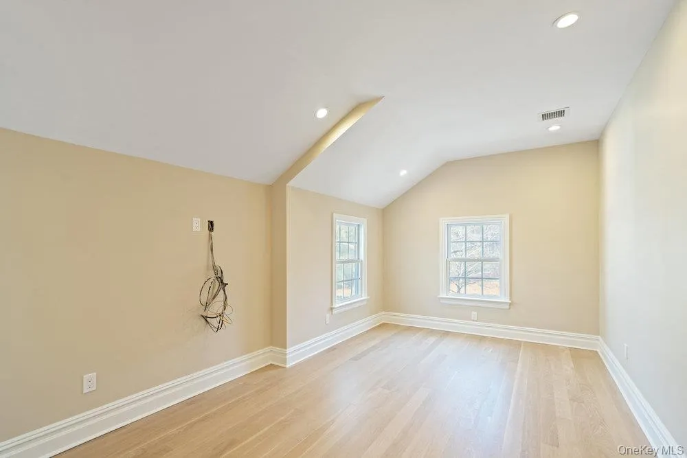 Empty room with lofted ceiling, light wood-style floors, and recessed lighting Empty room with lofted ceiling, light wood-style floors, and recessed lighting