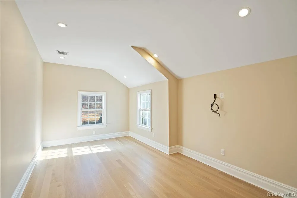 Spare room with vaulted ceiling, light wood-style floors, and recessed lighting Spare room with vaulted ceiling, light wood-style floors, and recessed lighting