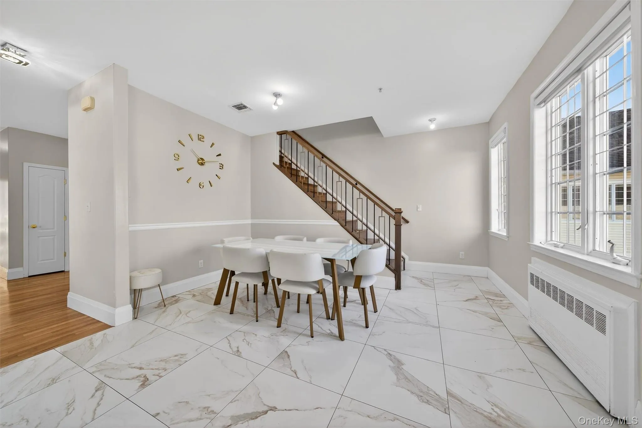 Dining area featuring radiator heating unit, stairway, and light marble finish floors Dining area featuring radiator heating unit, stairway, and light marble finish floors