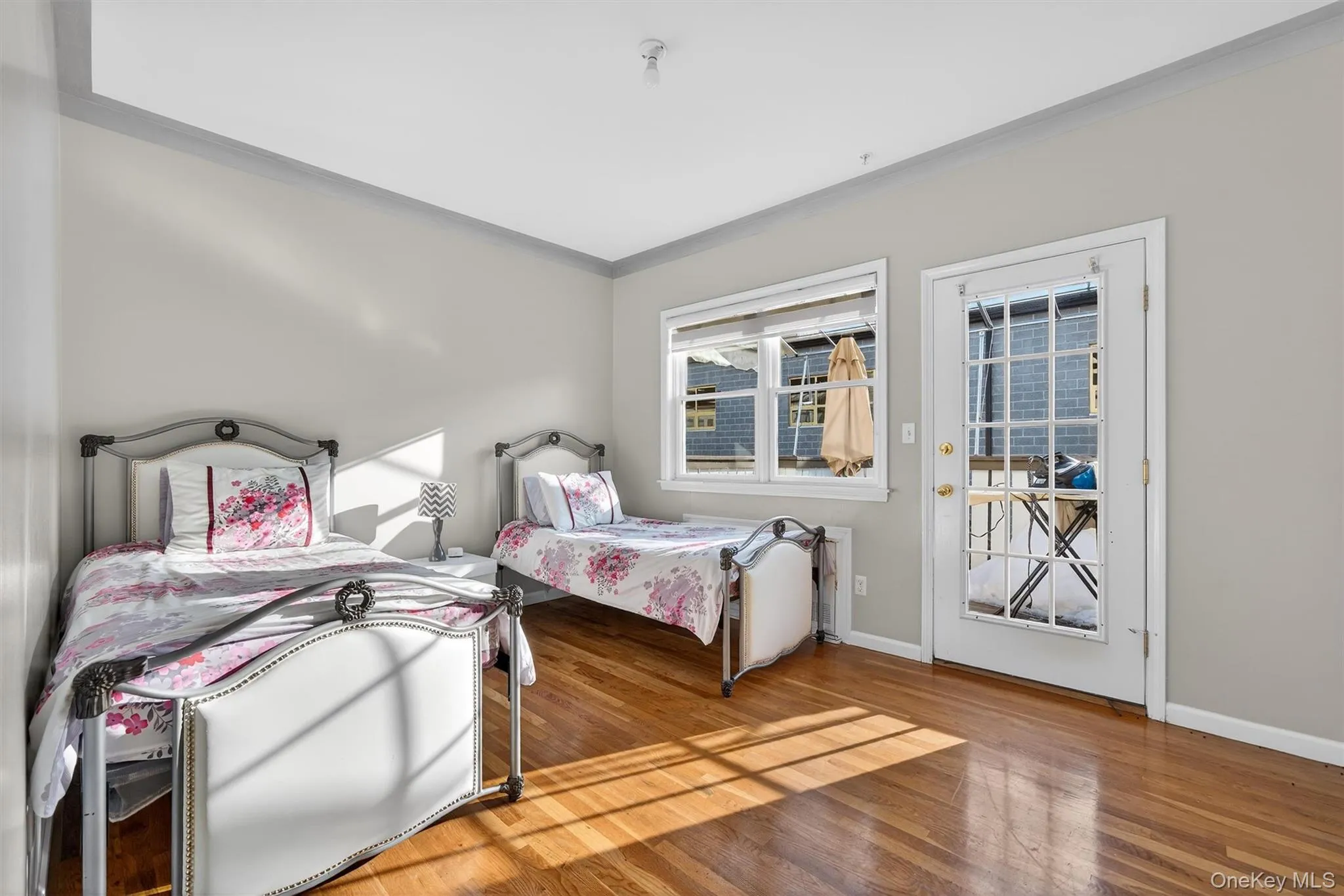 Bedroom with access to outside, crown molding, and wood finished floors Bedroom with access to outside, crown molding, and wood finished floors