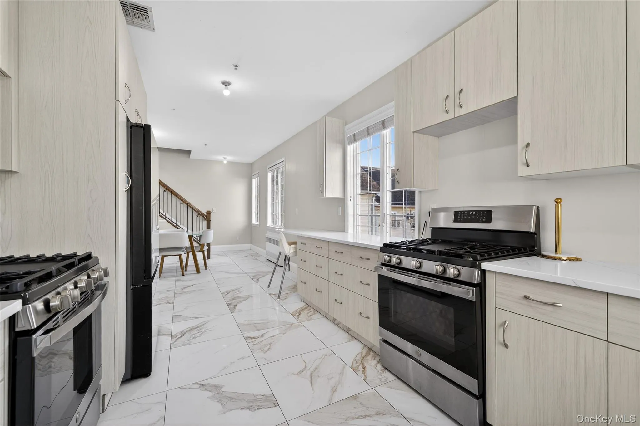 Kitchen with light brown cabinets, stainless steel gas range oven, and light marble finish floors Kitchen with light brown cabinets, stainless steel gas range oven, and light marble finish floors