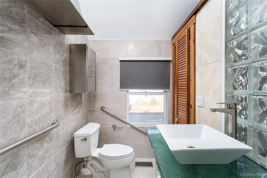 Half bathroom with tile walls, tile patterned flooring, and a closet Half bathroom with tile walls, tile patterned flooring, and a closet