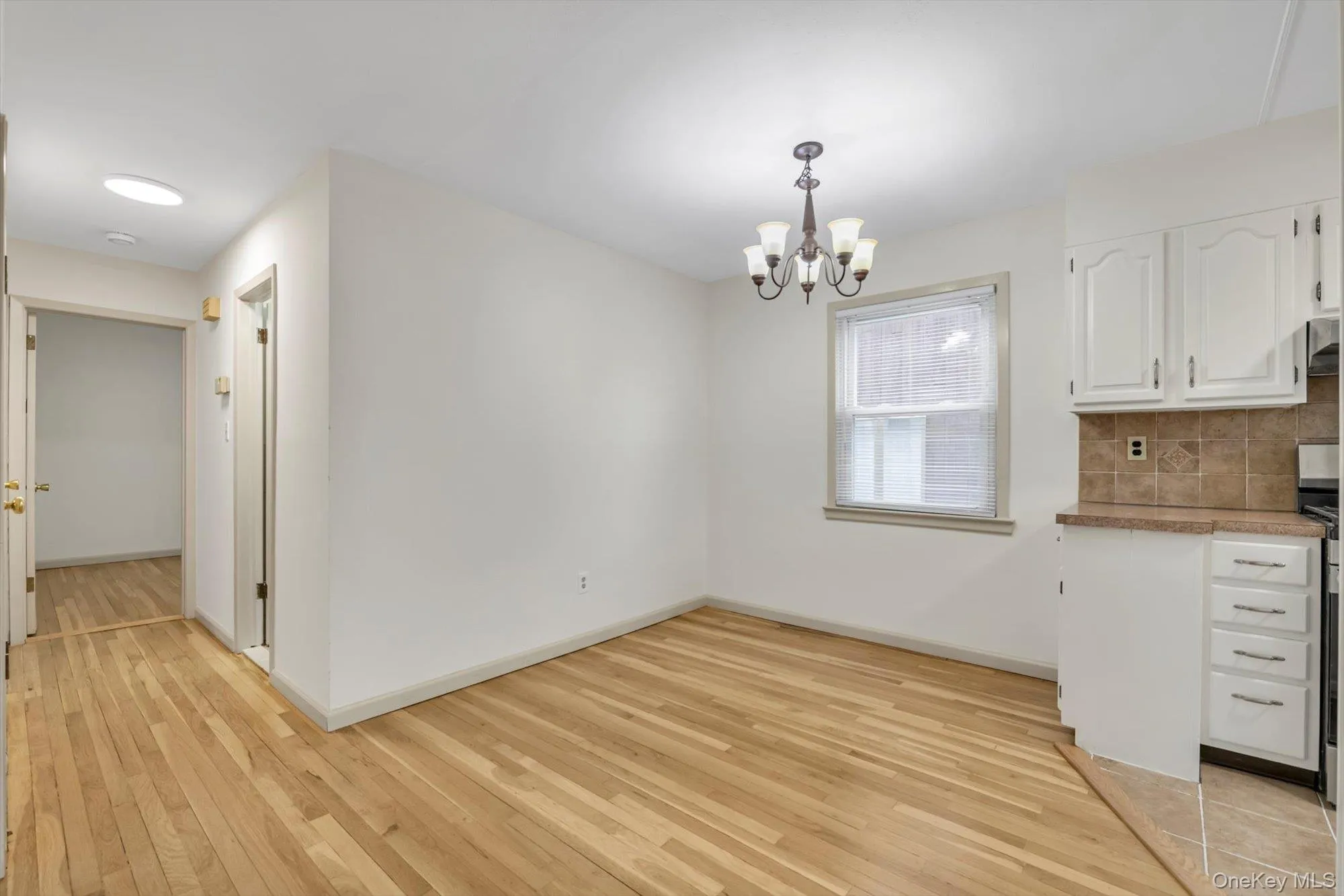 Unfurnished dining area featuring light wood-type flooring and a chandelier Unfurnished dining area featuring light wood-type flooring and a chandelier