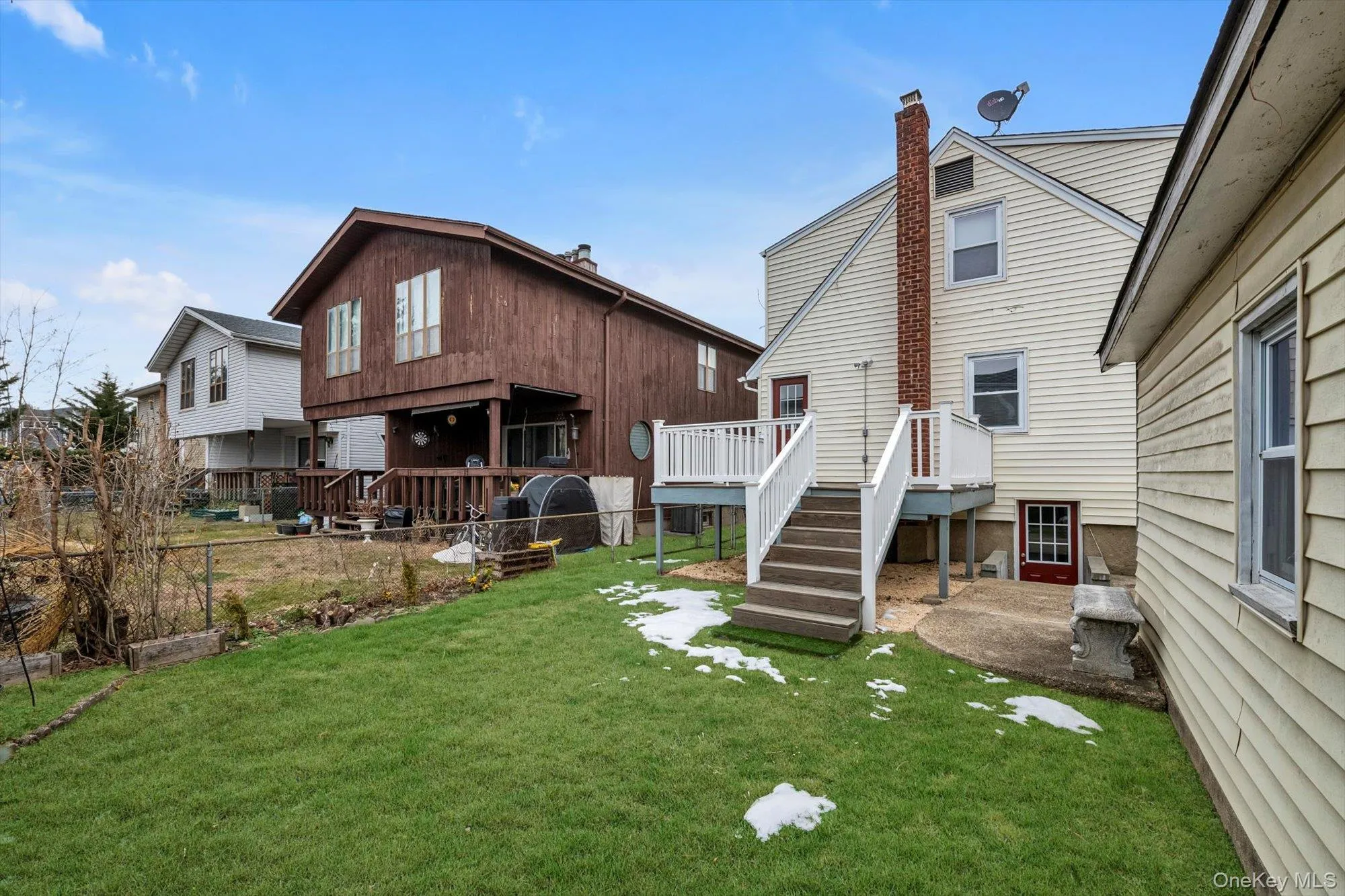 Rear view of house with a lawn, a chimney, stairway, a deck, and a patio area Rear view of house with a lawn, a chimney, stairway, a deck, and a patio area