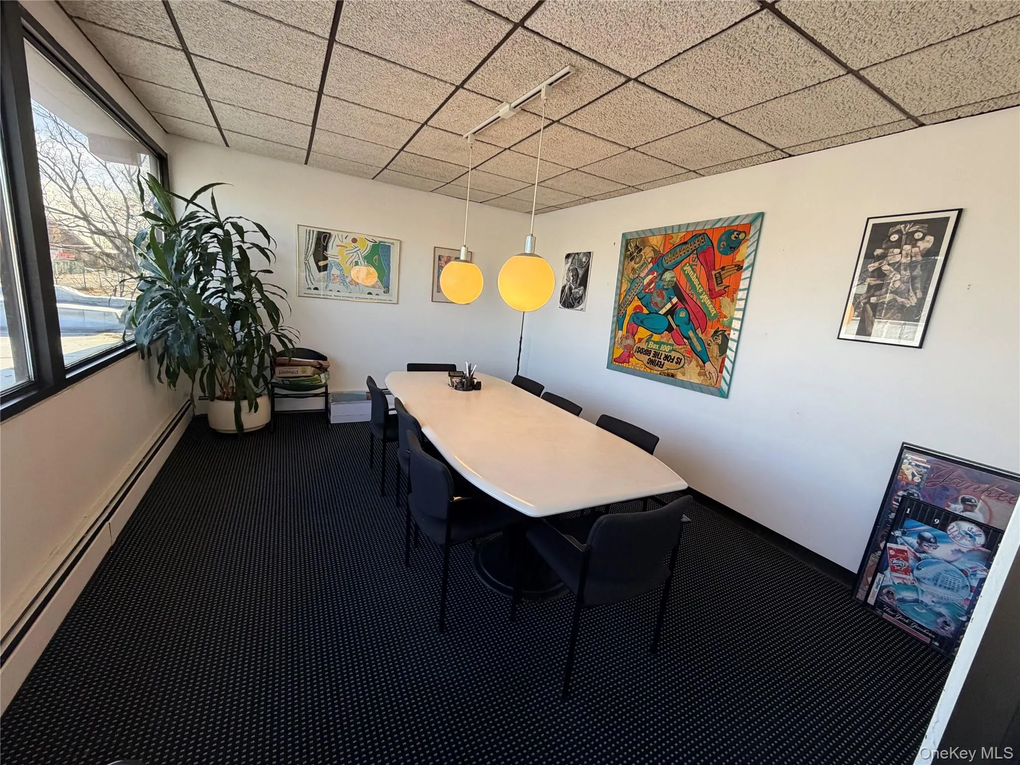 Dining area with a baseboard heating unit, a paneled ceiling, and dark colored carpet Dining area with a baseboard heating unit, a paneled ceiling, and dark colored carpet