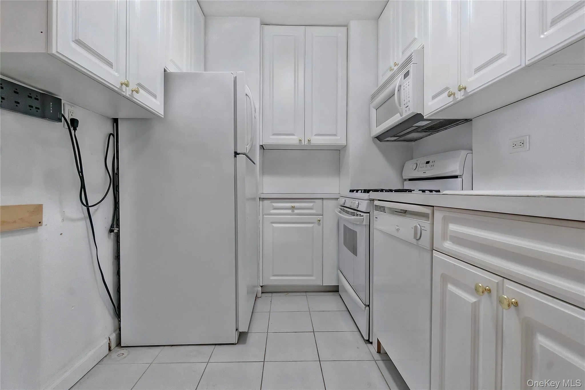 Kitchen with white appliances, white cabinets, light countertops, and light tile patterned flooring Kitchen with white appliances, white cabinets, light countertops, and light tile patterned flooring