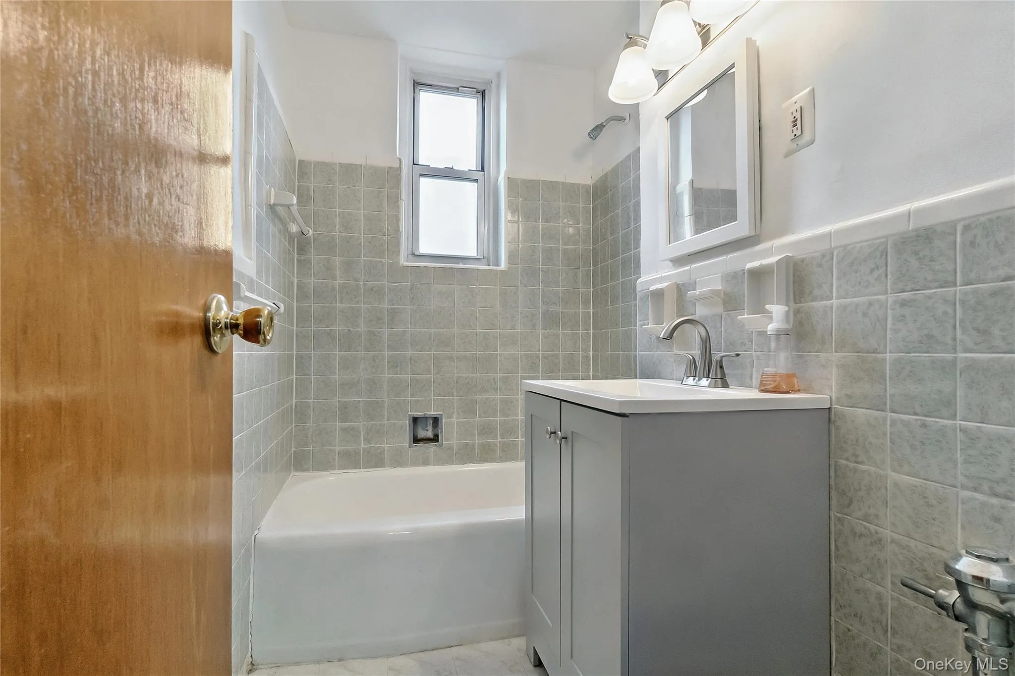 Full bathroom featuring vanity, shower / bath combination, and tile walls Full bathroom featuring vanity, shower / bath combination, and tile walls