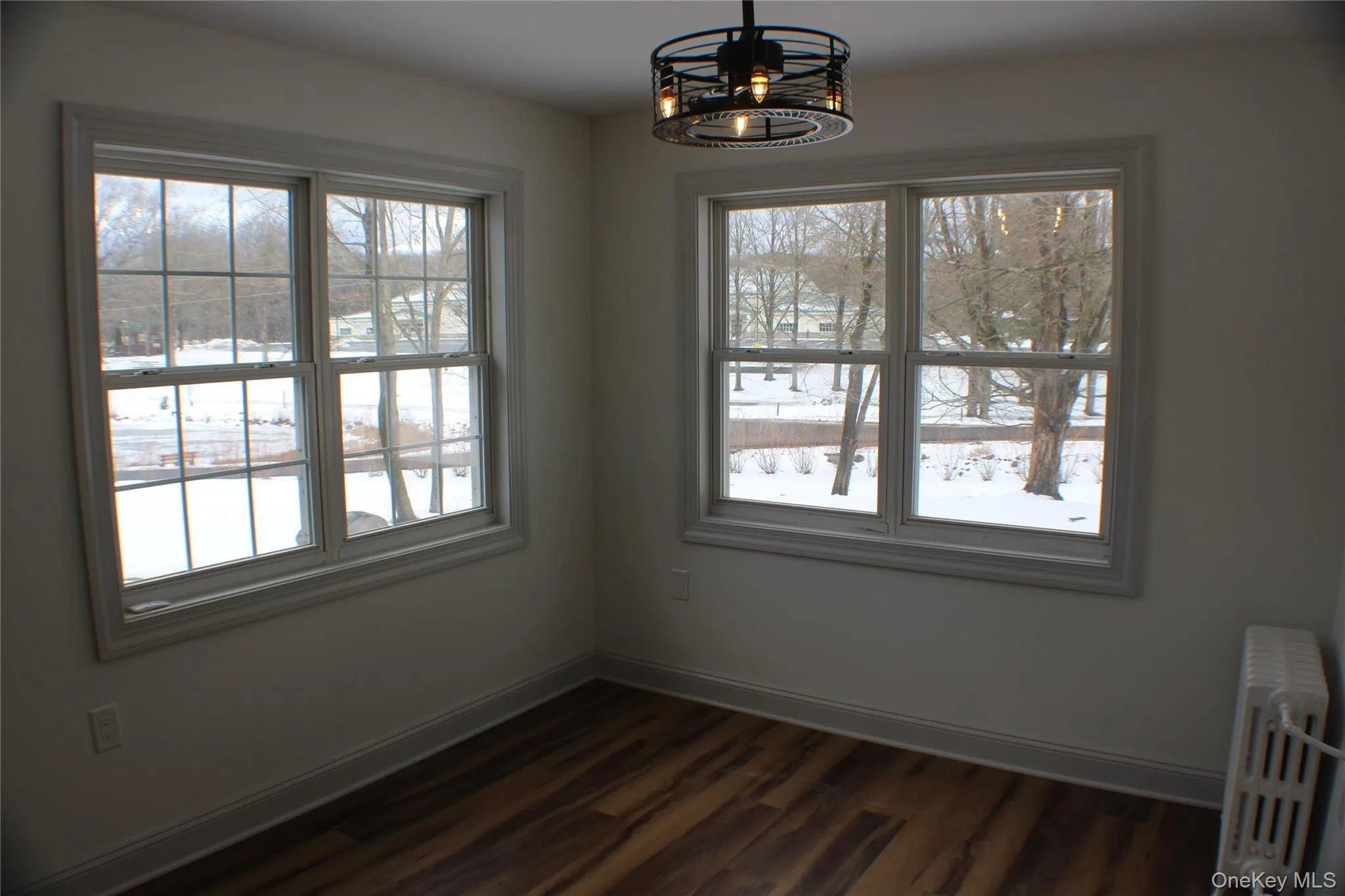 Unfurnished dining area with radiator, dark wood finished floors, and a chandelier Unfurnished dining area with radiator, dark wood finished floors, and a chandelier