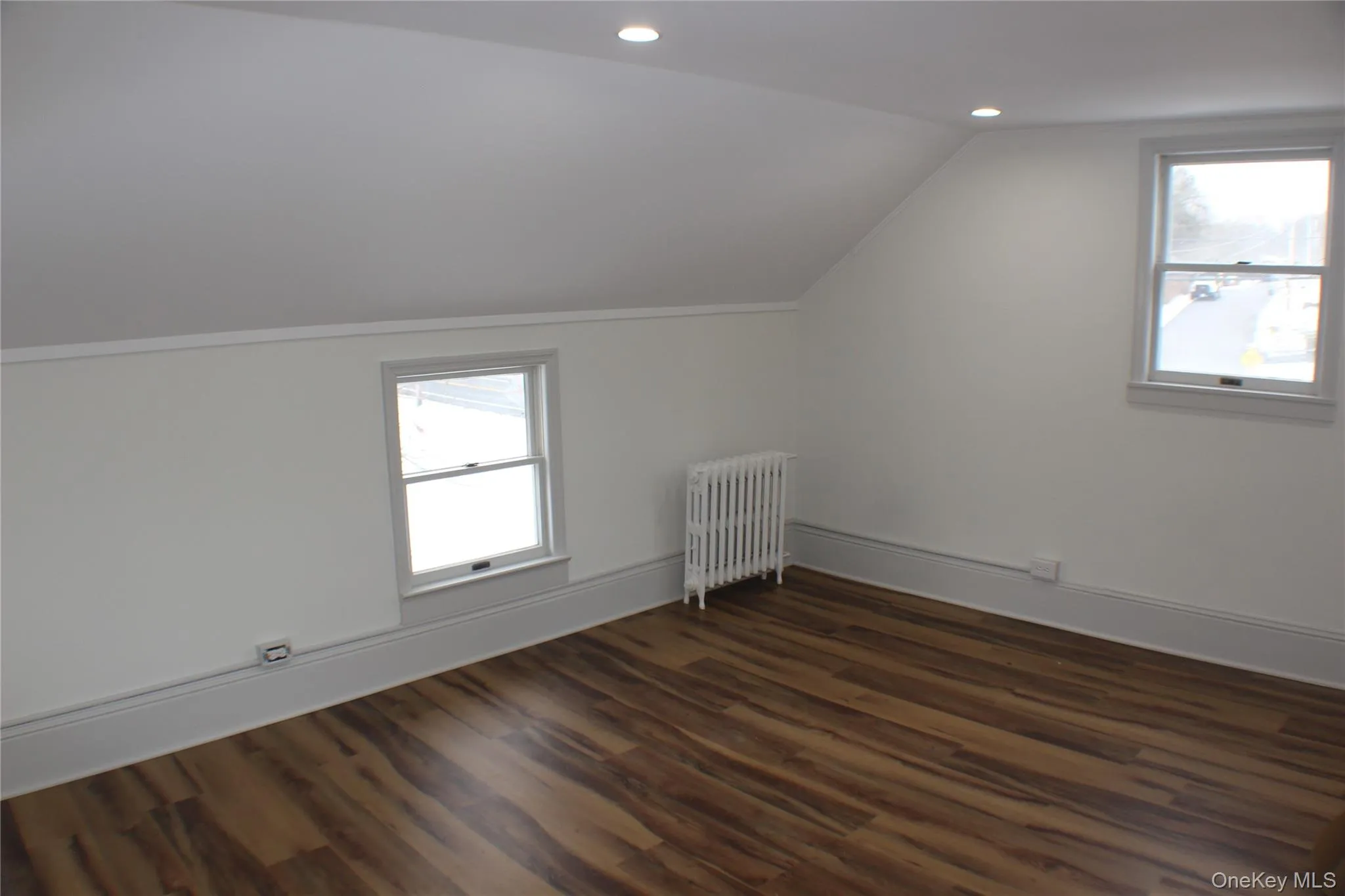 Bonus room featuring radiator, lofted ceiling, dark wood finished floors, and recessed lighting Bonus room featuring radiator, lofted ceiling, dark wood finished floors, and recessed lighting