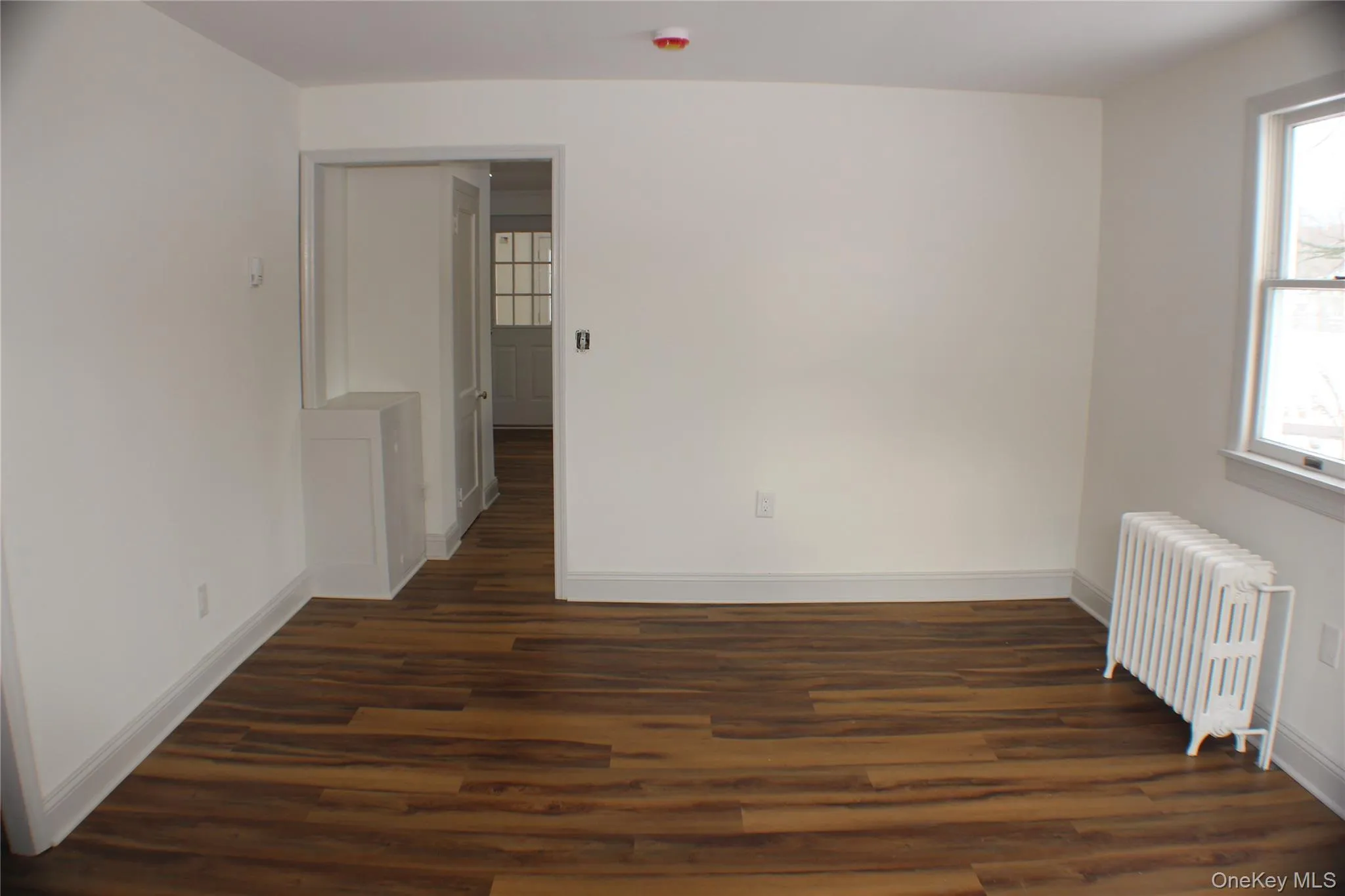 Empty room with radiator heating unit and dark wood finished floors Empty room with radiator heating unit and dark wood finished floors