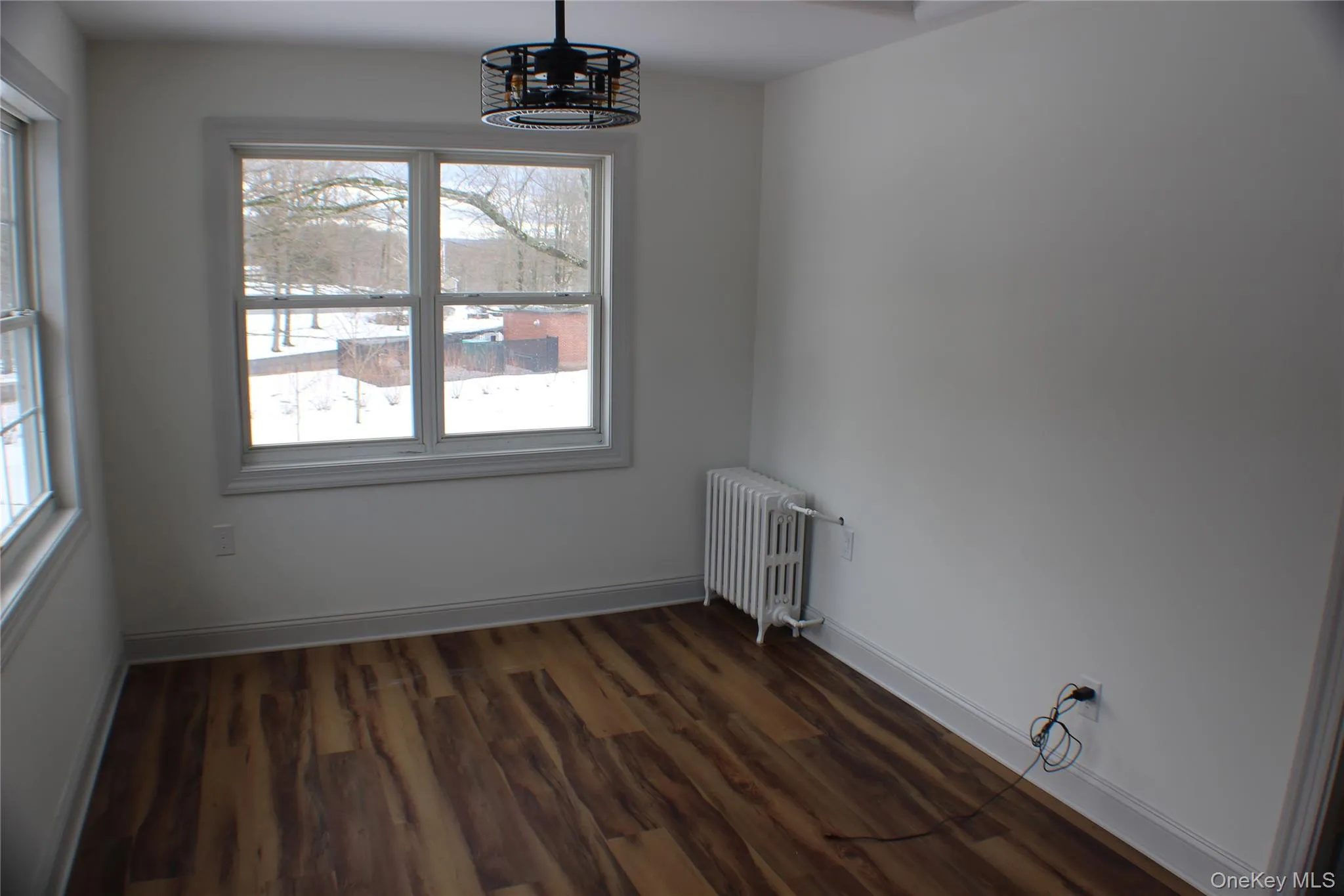 Unfurnished dining area featuring radiator heating unit, dark wood-type flooring, and a chandelier Unfurnished dining area featuring radiator heating unit, dark wood-type flooring, and a chandelier