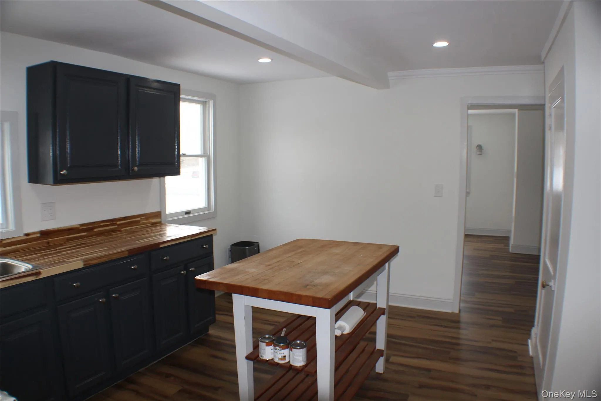 Kitchen with dark wood-style flooring, recessed lighting, butcher block counters, and dark cabinets Kitchen with dark wood-style flooring, recessed lighting, butcher block counters, and dark cabinets