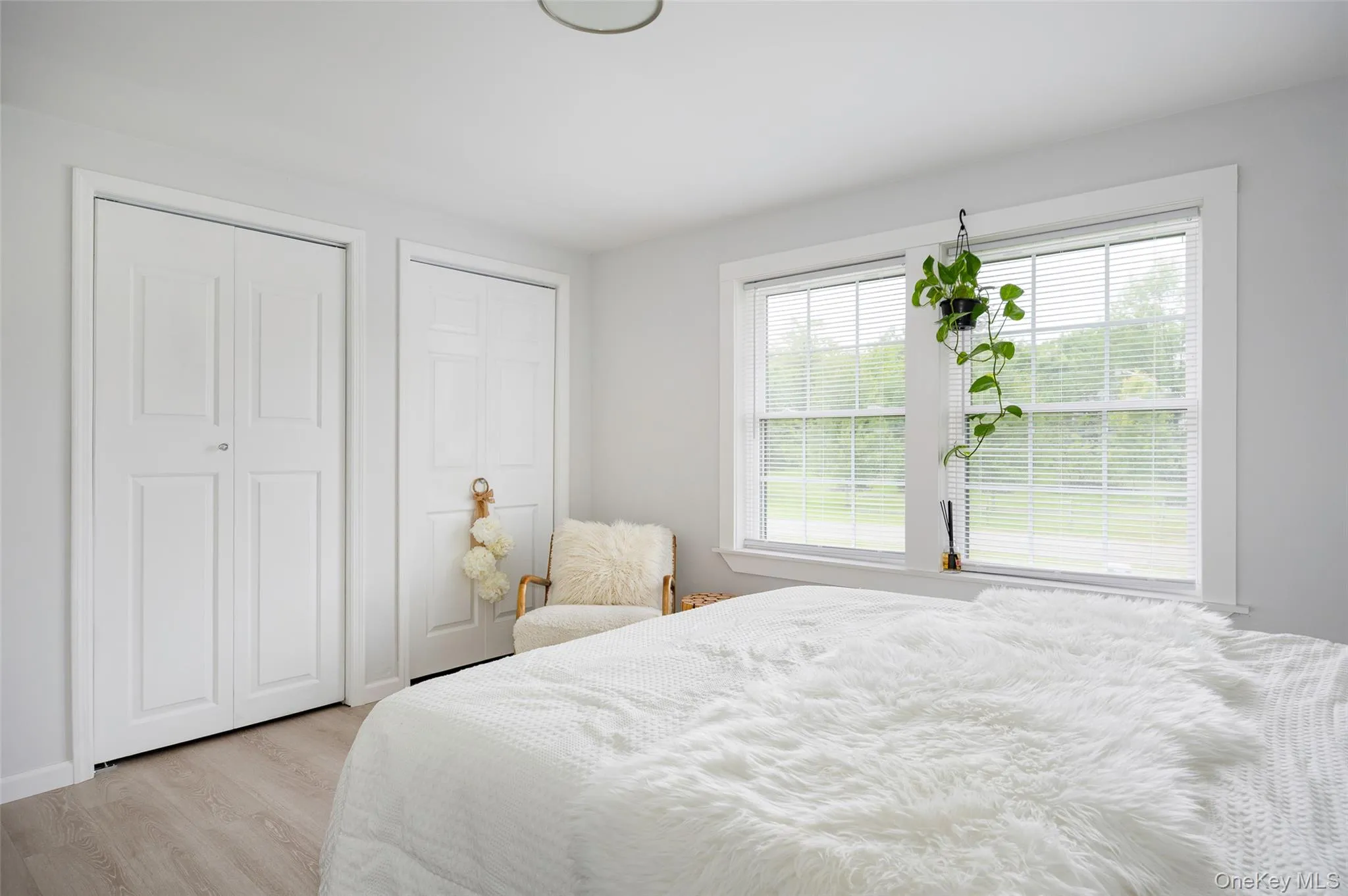 Bedroom featuring light wood-type flooring and multiple closets Bedroom featuring light wood-type flooring and multiple closets