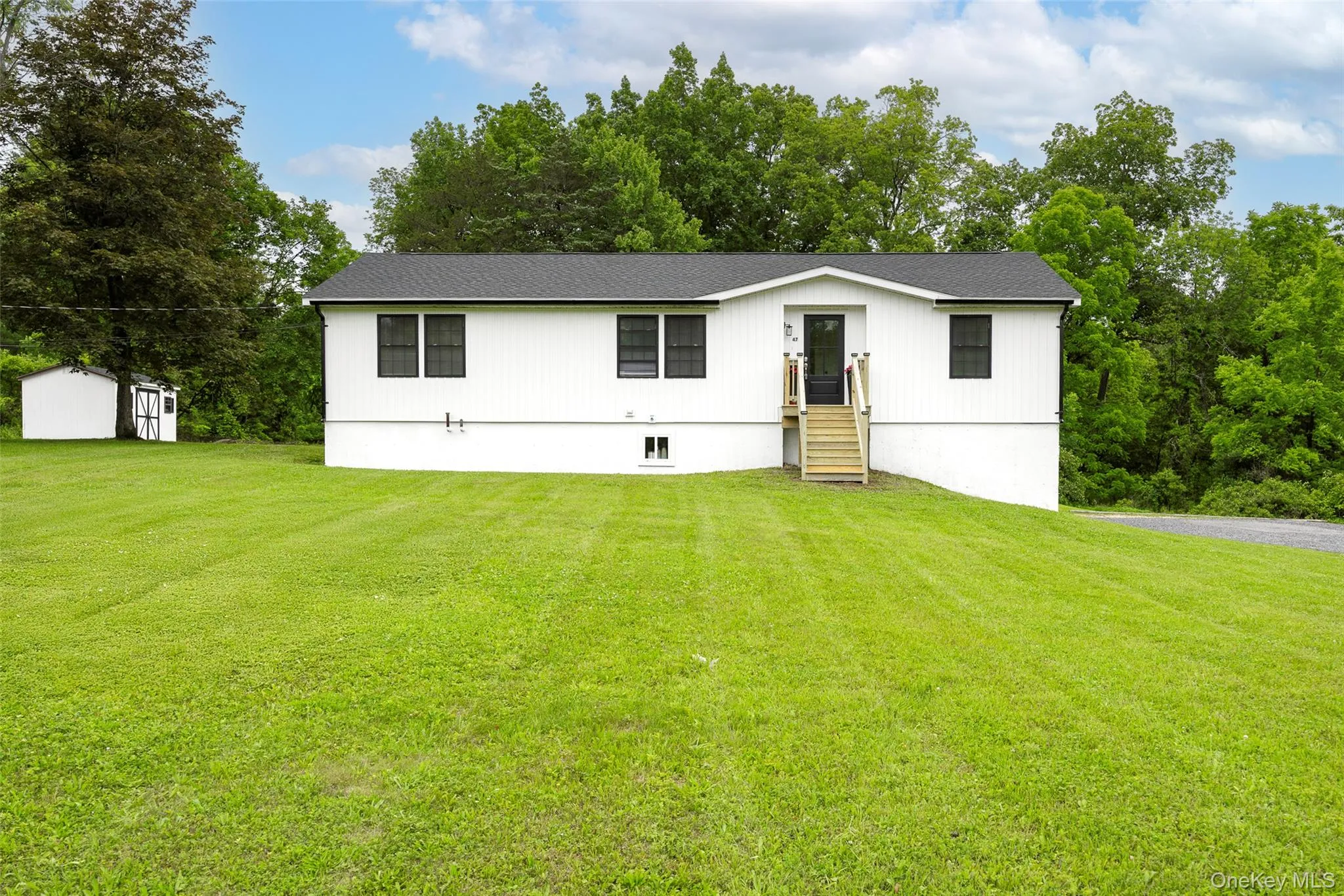 View of front of home featuring a front lawn, a shed, and a shingled roof View of front of home featuring a front lawn, a shed, and a shingled roof