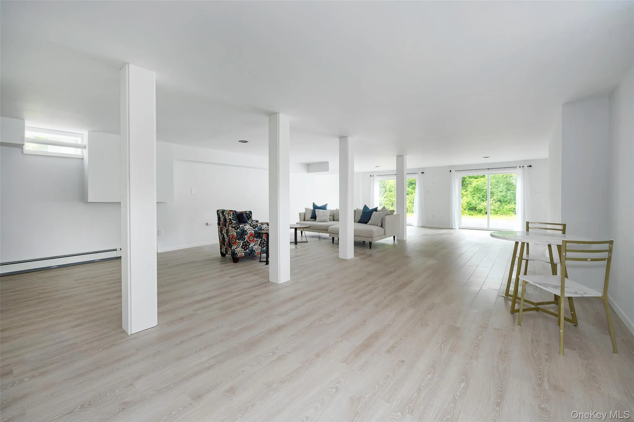 Below grade area featuring light wood finished floors and a baseboard heating unit Below grade area featuring light wood finished floors and a baseboard heating unit