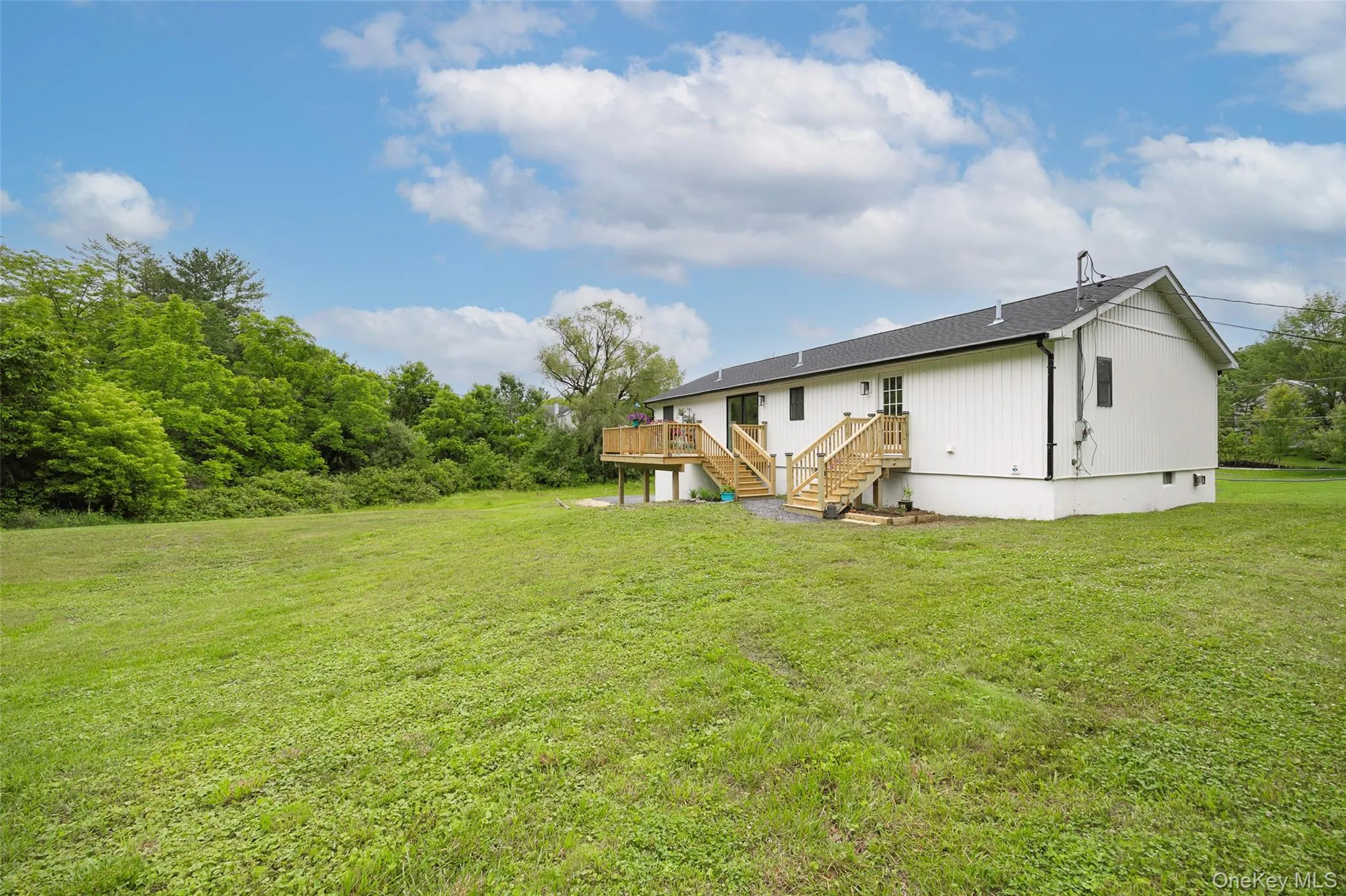 Back of house with stairway, a wooden deck, and a lawn Back of house with stairway, a wooden deck, and a lawn