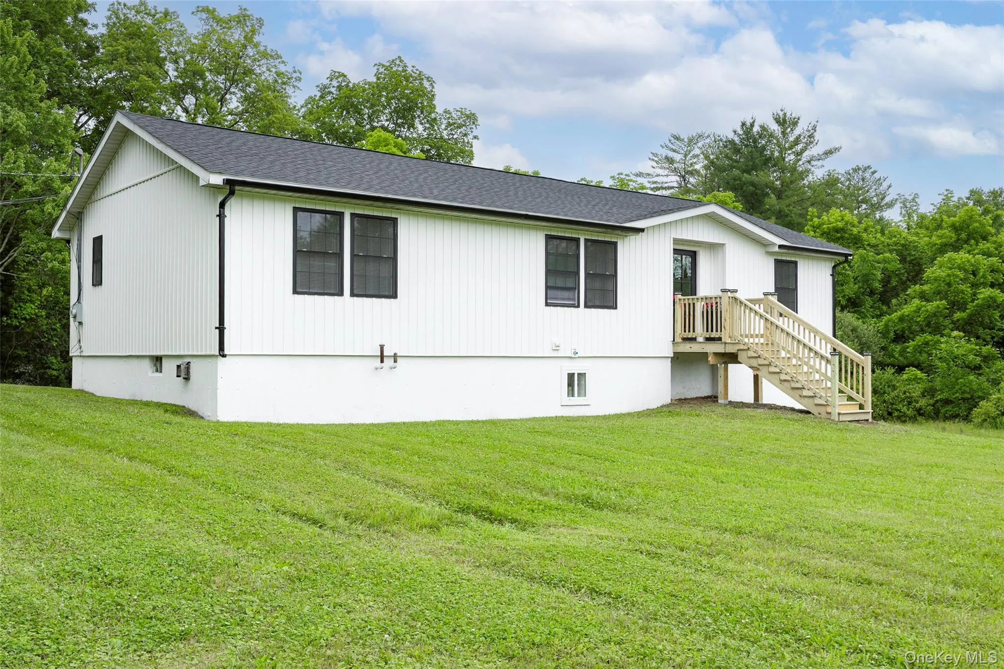 View of front facade with a front lawn, roof with shingles, and stairs View of front facade with a front lawn, roof with shingles, and stairs