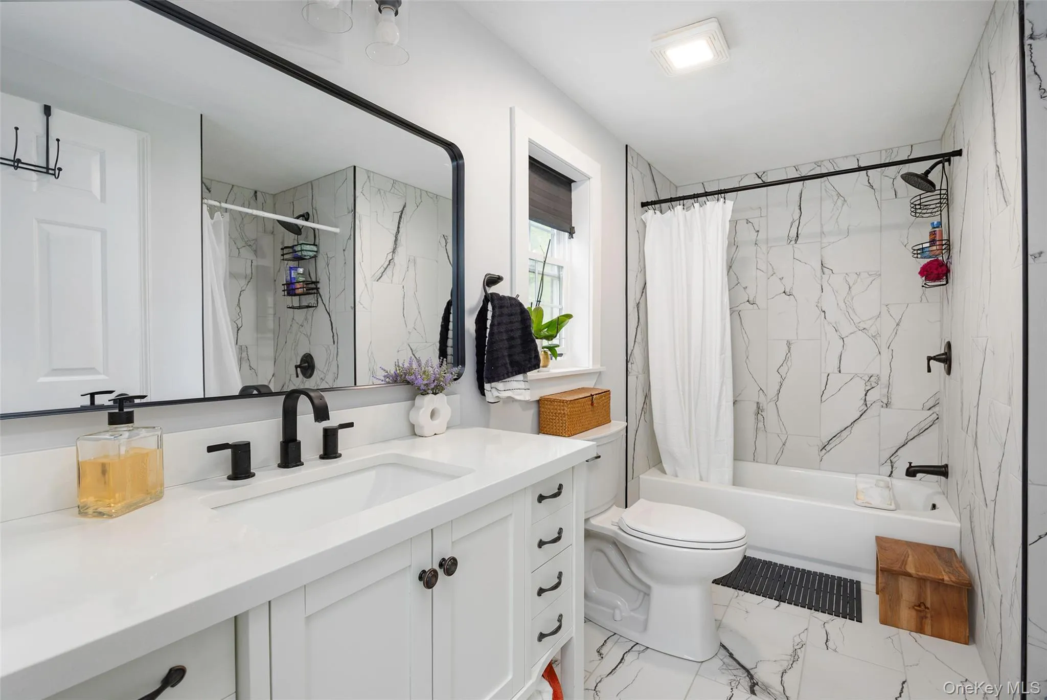 Bathroom featuring vanity, marble finish floors, and shower / tub combo with curtain Bathroom featuring vanity, marble finish floors, and shower / tub combo with curtain