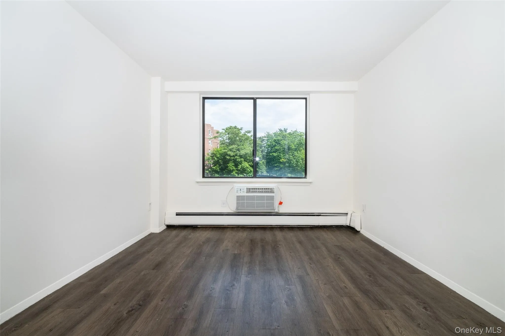 Unfurnished room with dark wood-style flooring and a baseboard heating unit Unfurnished room with dark wood-style flooring and a baseboard heating unit
