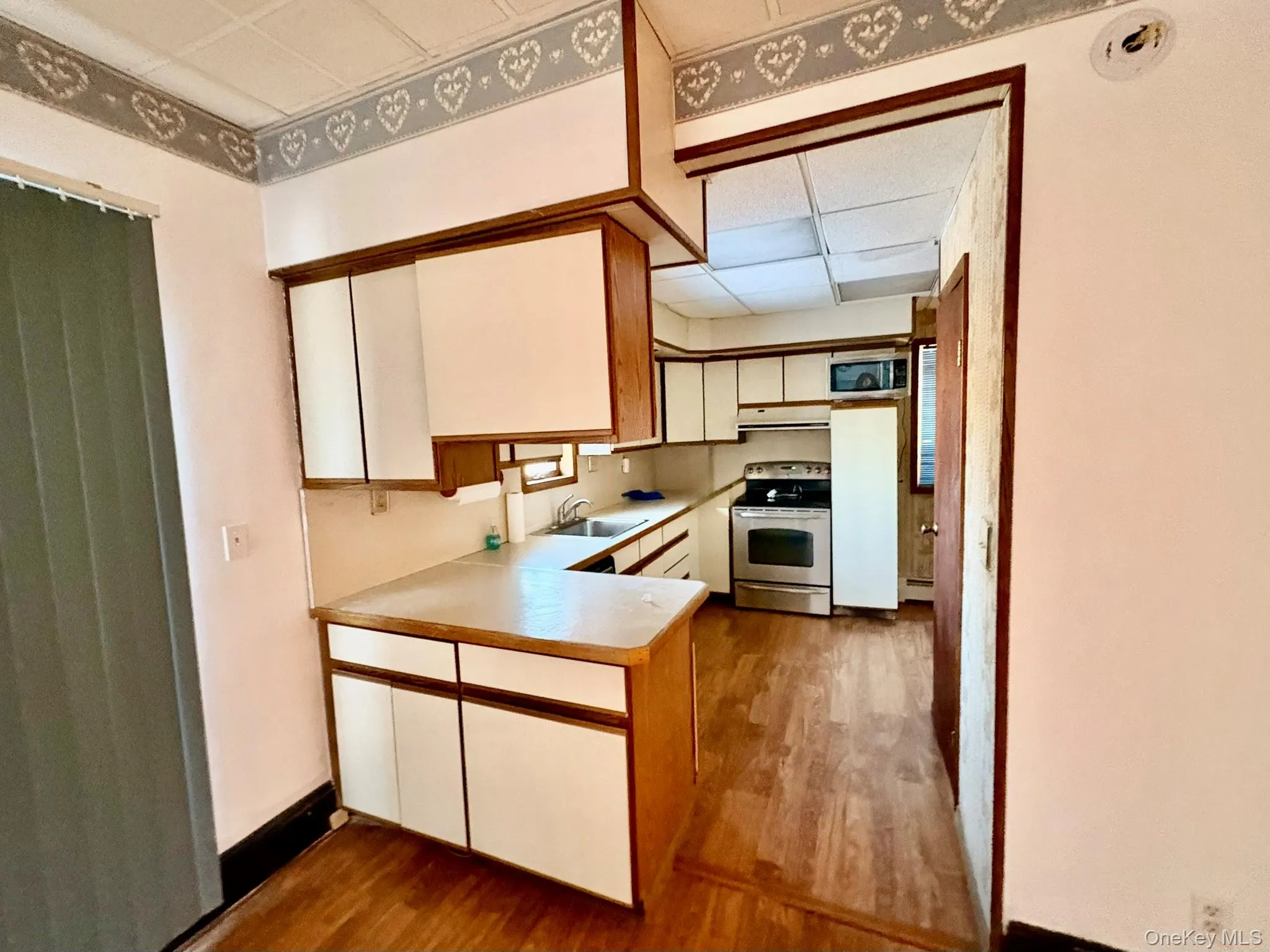Kitchen featuring white cabinets, stainless steel electric stove, light countertops, and dark wood-style flooring Kitchen featuring white cabinets, stainless steel electric stove, light countertops, and dark wood-style flooring