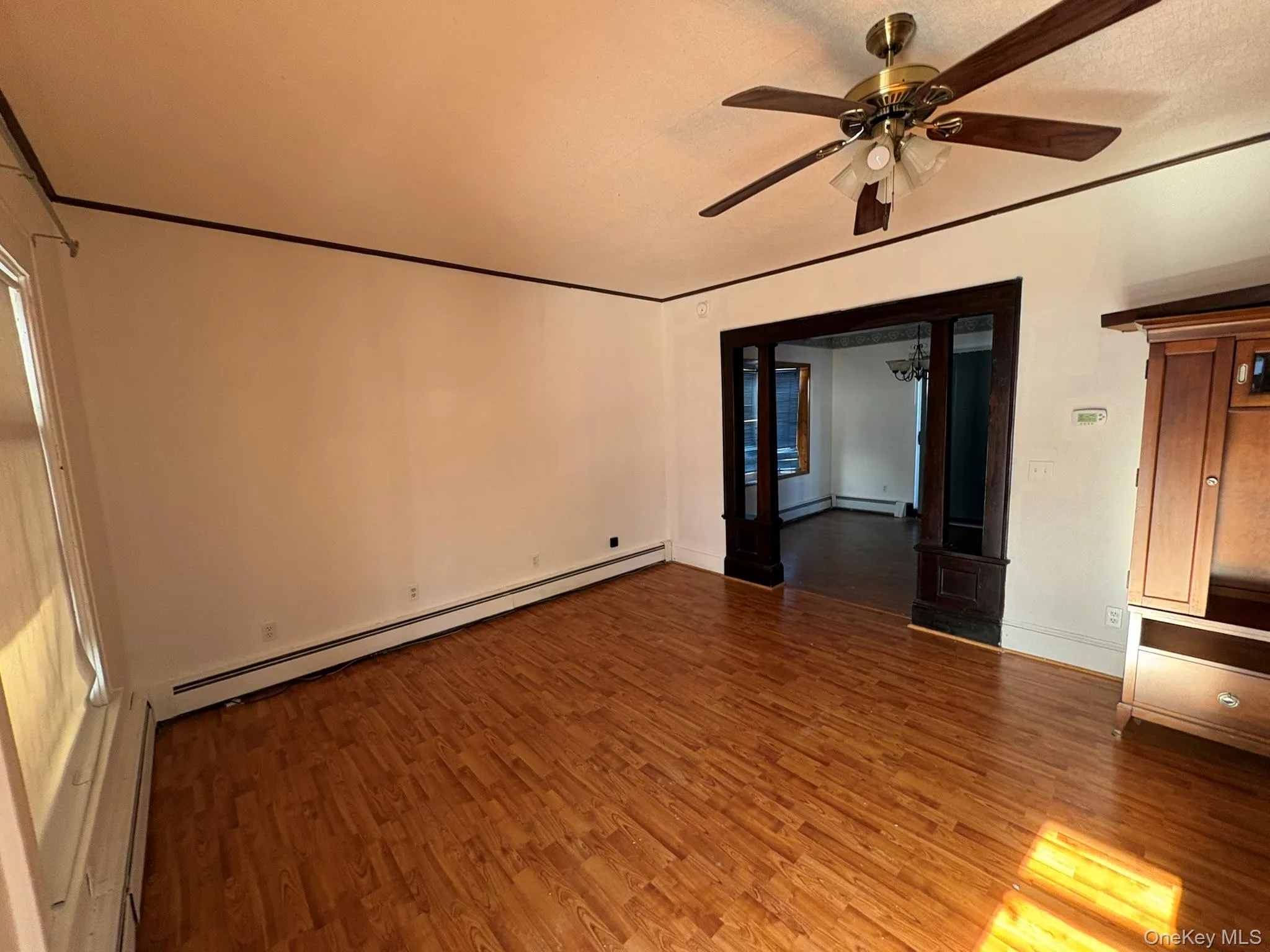 Empty room featuring a baseboard heating unit, ceiling fan, dark wood finished floors, a baseboard radiator, and a textured ceiling Empty room featuring a baseboard heating unit, ceiling fan, dark wood finished floors, a baseboard radiator, and a textured ceiling