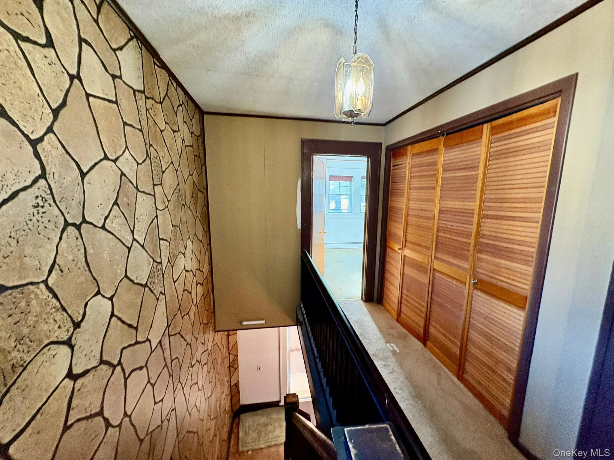 Corridor with ornamental molding, a chandelier, and a textured ceiling Corridor with ornamental molding, a chandelier, and a textured ceiling