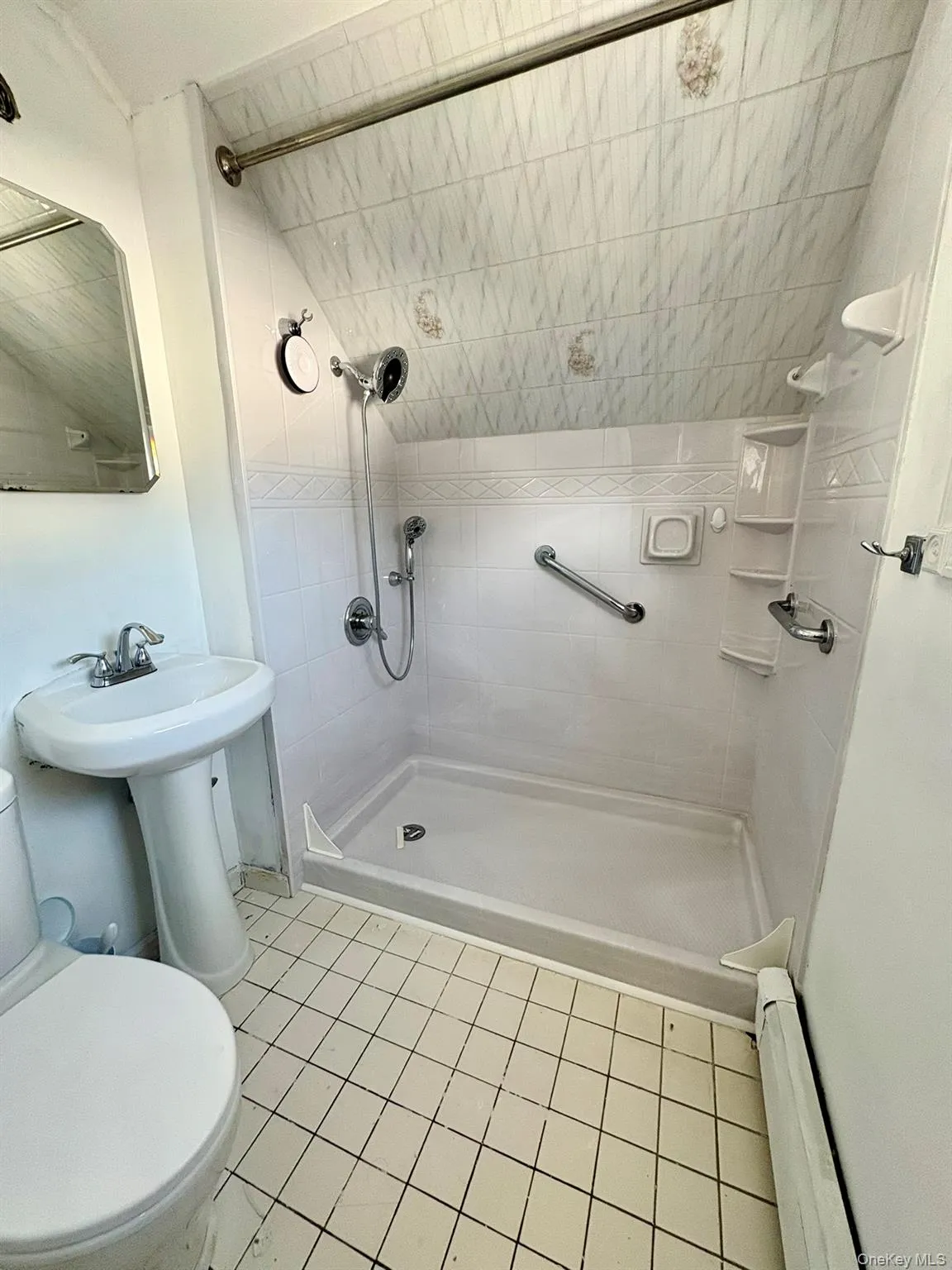 Full bath with a shower stall, a baseboard heating unit, and light tile patterned flooring Full bath with a shower stall, a baseboard heating unit, and light tile patterned flooring