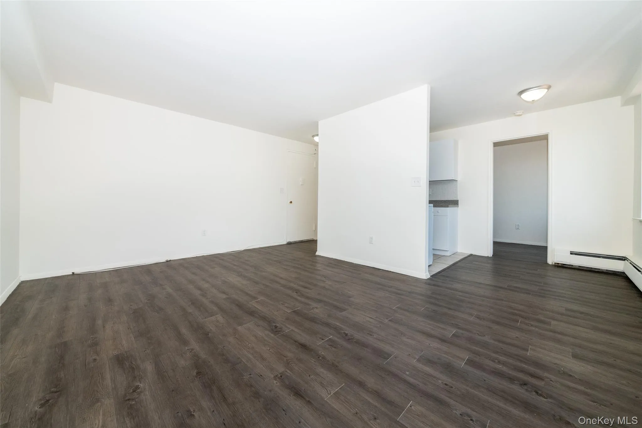 Unfurnished living room featuring dark wood-style flooring and baseboards Unfurnished living room featuring dark wood-style flooring and baseboards