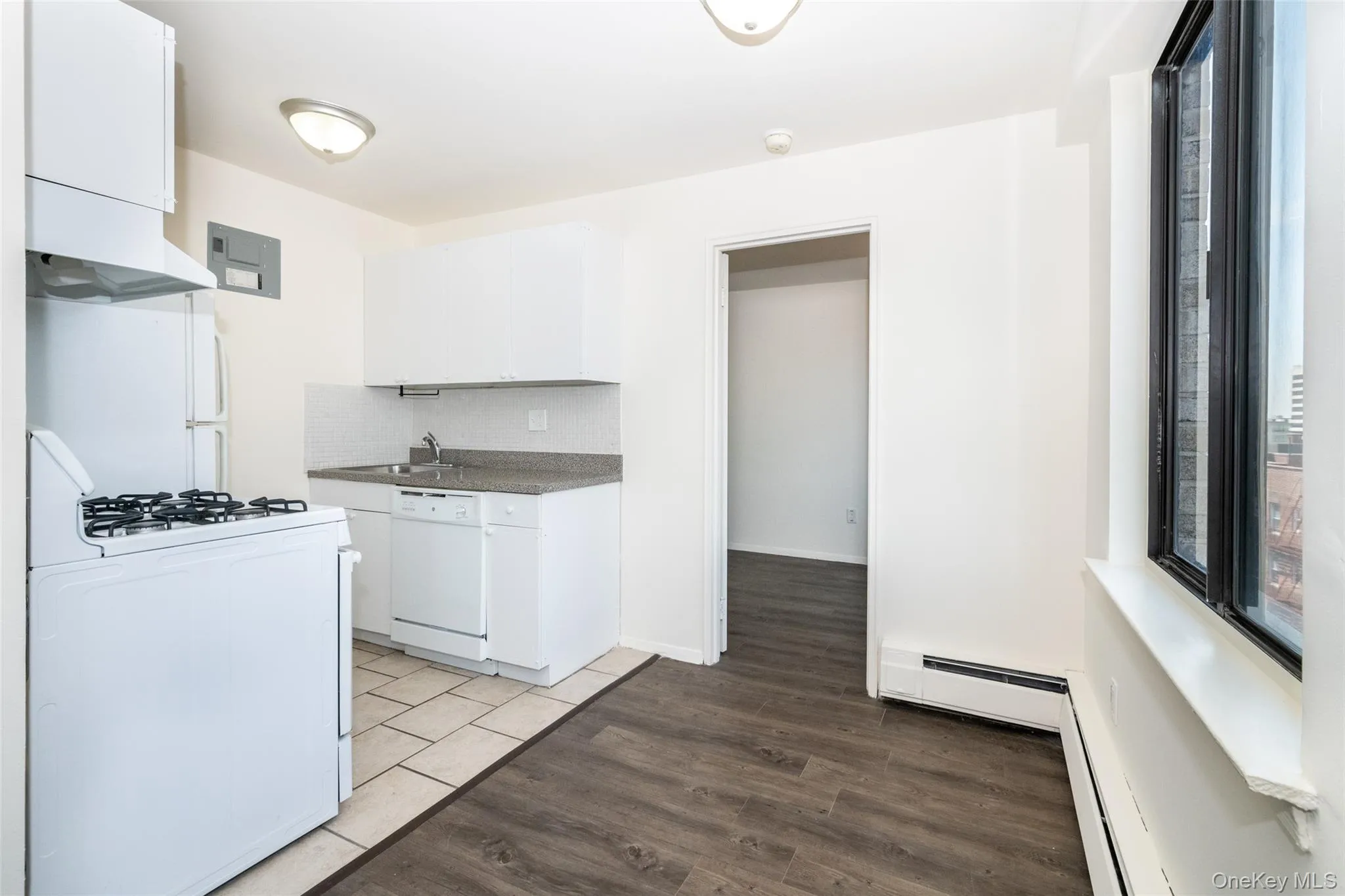 Kitchen featuring white appliances, backsplash, range hood, white cabinetry, and dark wood-style flooring Kitchen featuring white appliances, backsplash, range hood, white cabinetry, and dark wood-style flooring