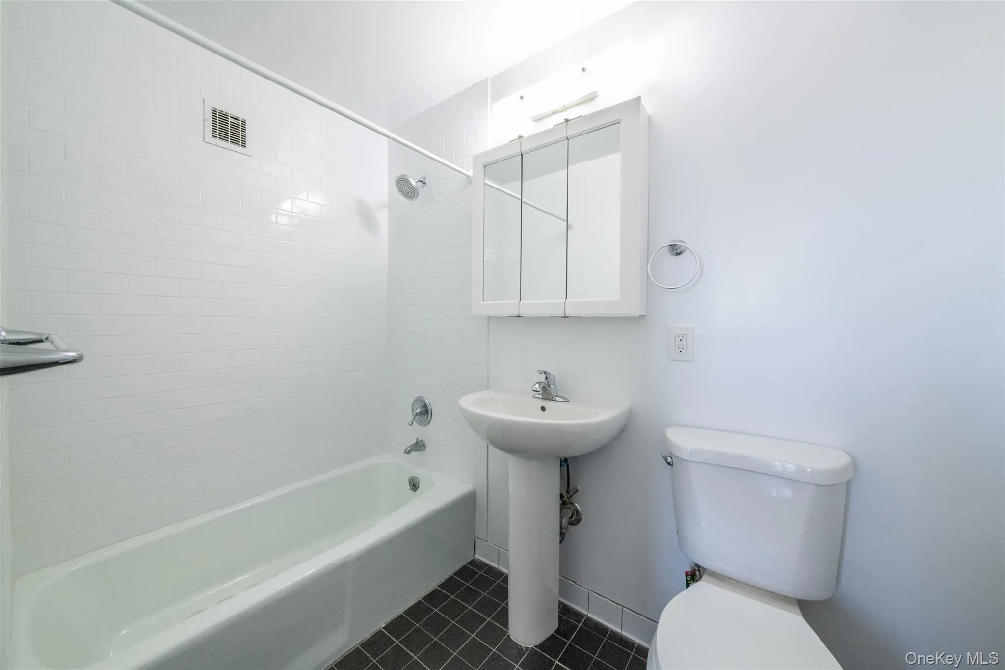 Bathroom featuring shower / washtub combination and dark tile patterned floors Bathroom featuring shower / washtub combination and dark tile patterned floors