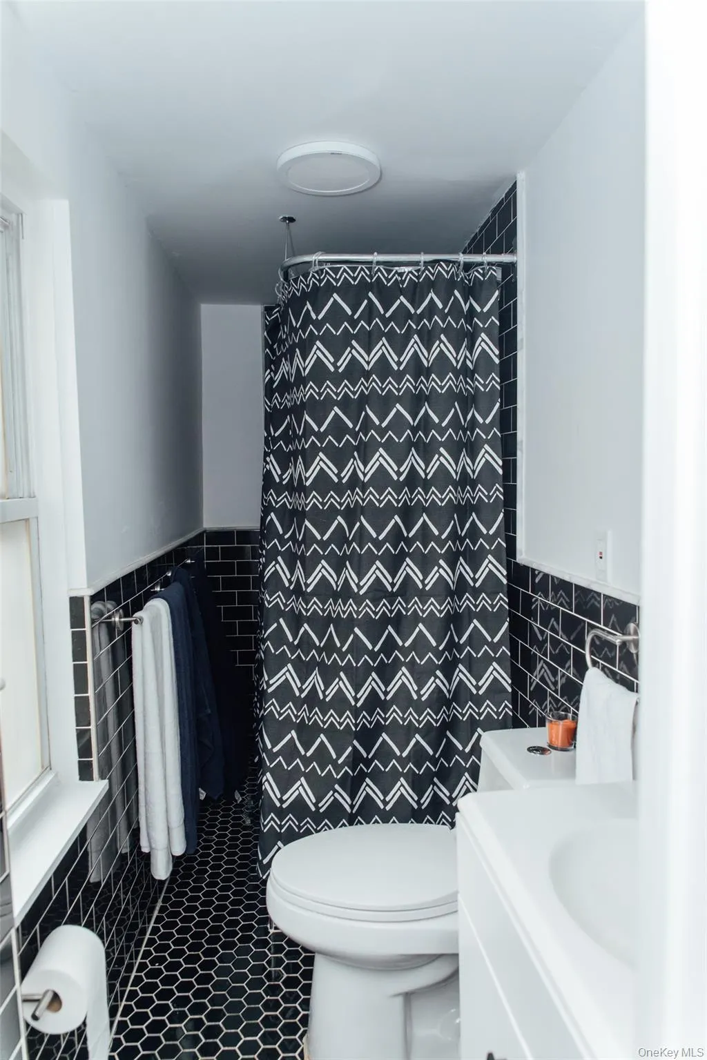 Bathroom featuring tile walls, vanity, a wainscoted wall, tile patterned flooring, and curtained shower Bathroom featuring tile walls, vanity, a wainscoted wall, tile patterned flooring, and curtained shower