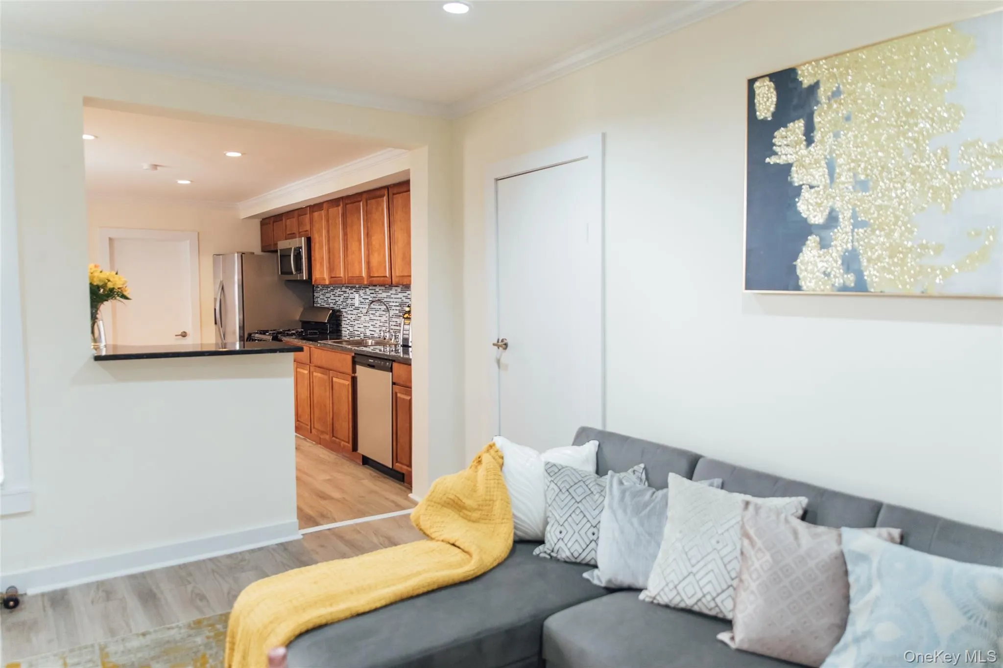 Living area with ornamental molding, light wood finished floors, and recessed lighting Living area with ornamental molding, light wood finished floors, and recessed lighting