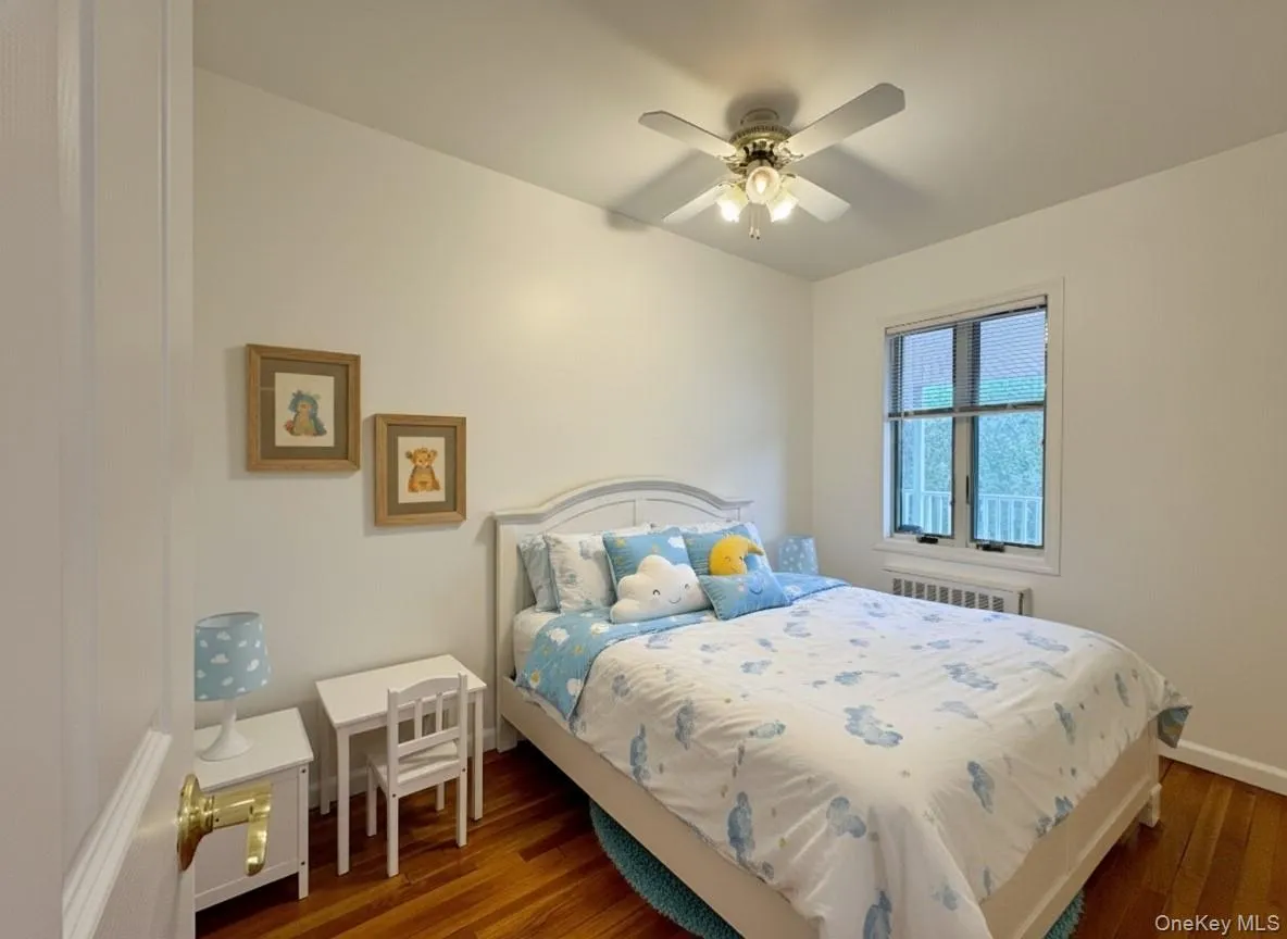 Bedroom featuring wood finished floors, a ceiling fan, and radiator Bedroom featuring wood finished floors, a ceiling fan, and radiator