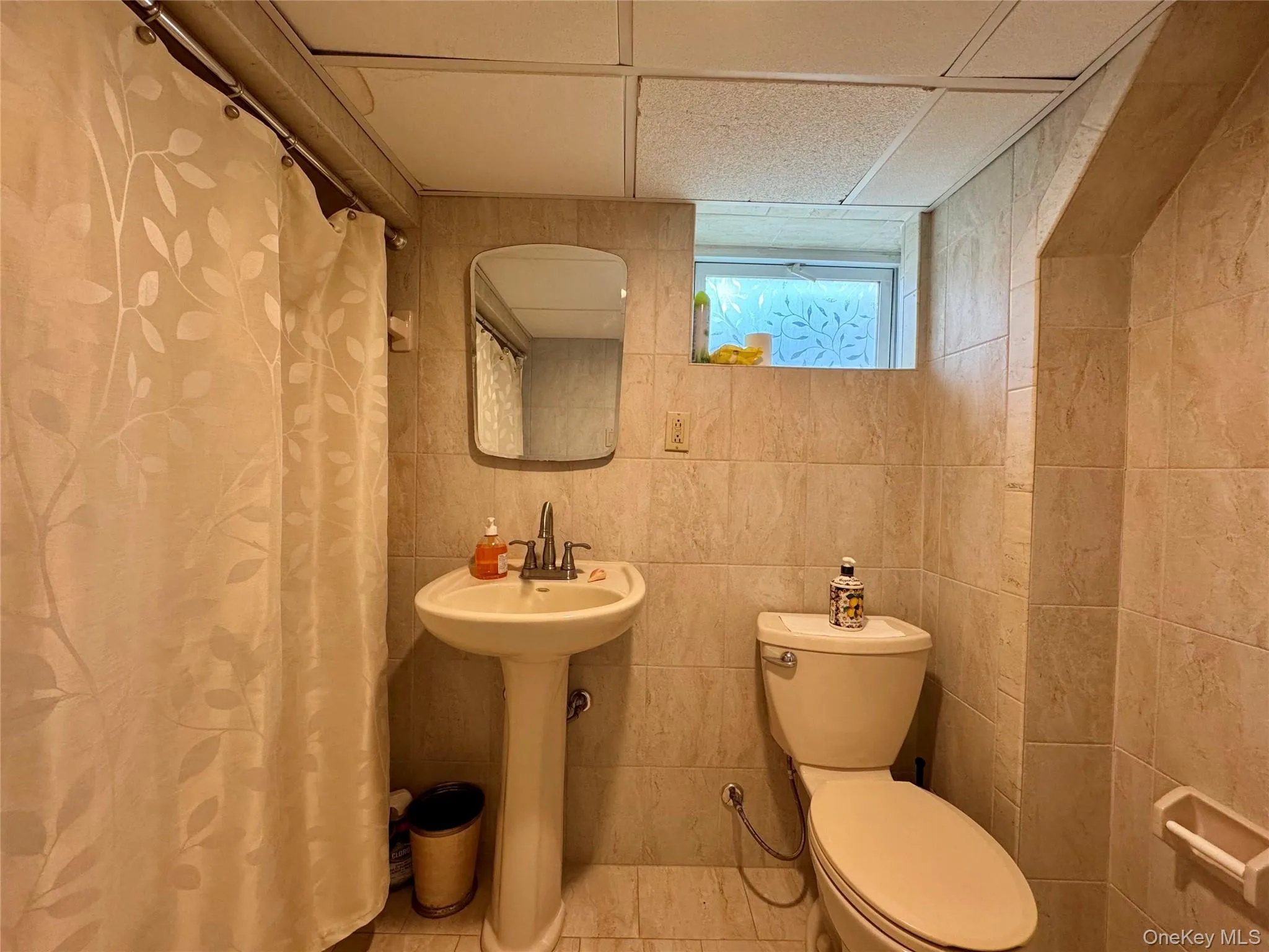 Full bathroom with a shower with curtain and tile walls Full bathroom with a shower with curtain and tile walls