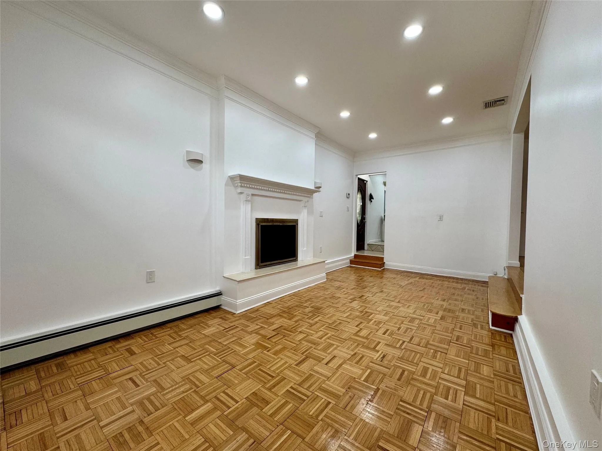 Unfurnished living room with a baseboard heating unit, ornamental molding, recessed lighting, and a fireplace with raised hearth Unfurnished living room with a baseboard heating unit, ornamental molding, recessed lighting, and a fireplace with raised hearth