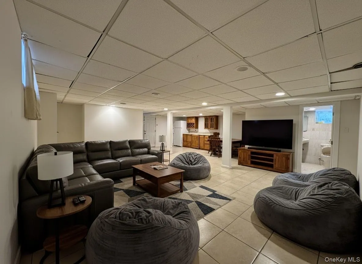 Living area featuring light tile patterned floors and a drop ceiling Living area featuring light tile patterned floors and a drop ceiling
