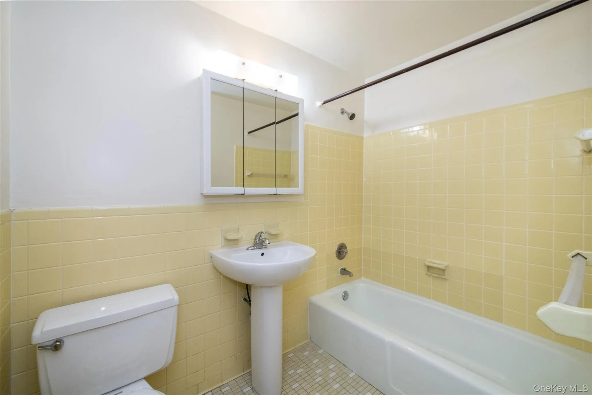Full bath featuring shower / bathtub combination, wainscoting, tile walls, and tile patterned flooring Full bath featuring shower / bathtub combination, wainscoting, tile walls, and tile patterned flooring