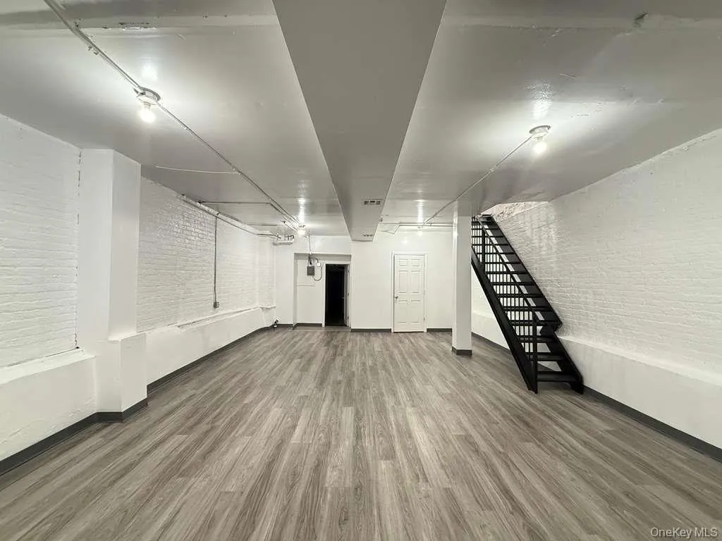 Finished basement featuring brick wall, wood finished floors, and stairs Finished basement featuring brick wall, wood finished floors, and stairs