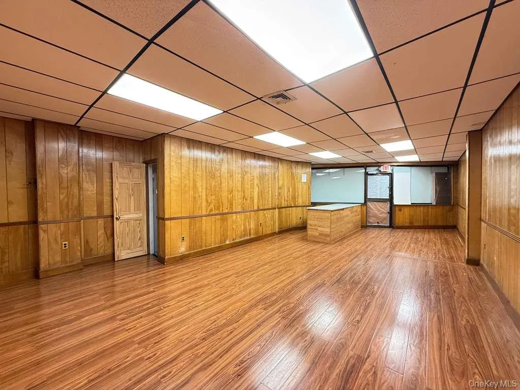 Finished basement with wooden walls, light wood-style flooring, and a drop ceiling Finished basement with wooden walls, light wood-style flooring, and a drop ceiling