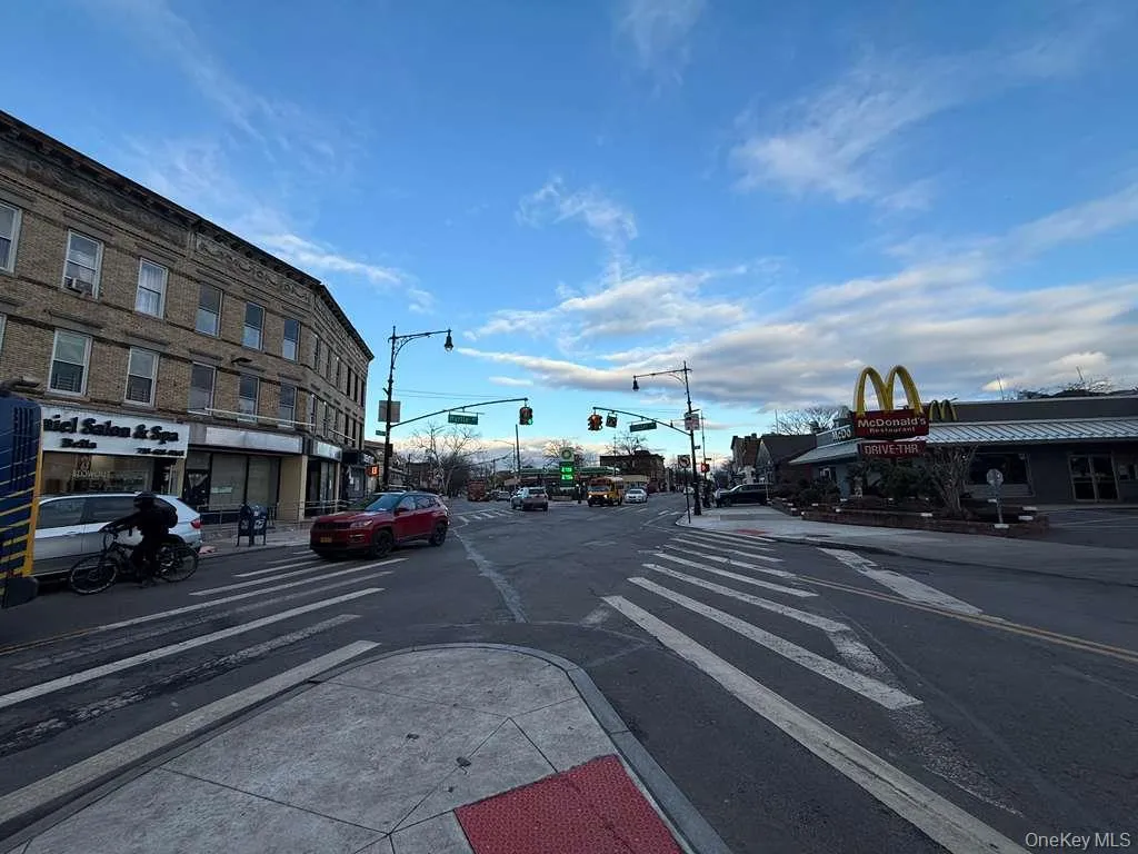 View of asphalt road featuring sidewalks, traffic lights, curbs, and street lights View of asphalt road featuring sidewalks, traffic lights, curbs, and street lights
