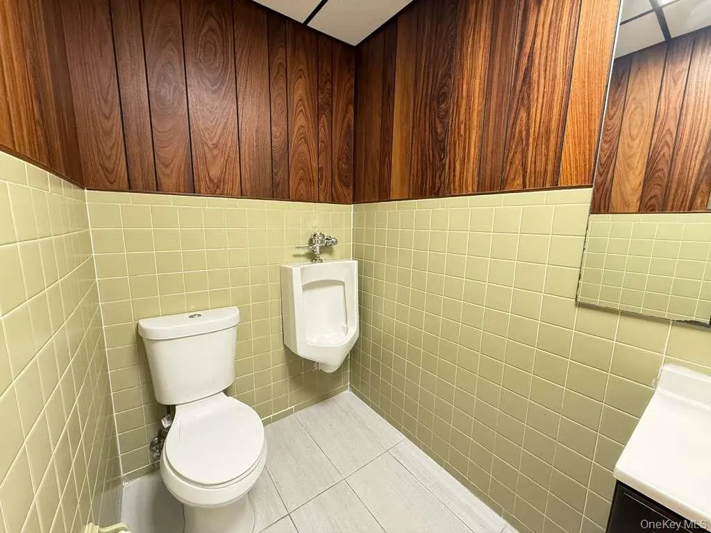 Bathroom with vanity, light tile patterned floors, and tile walls Bathroom with vanity, light tile patterned floors, and tile walls