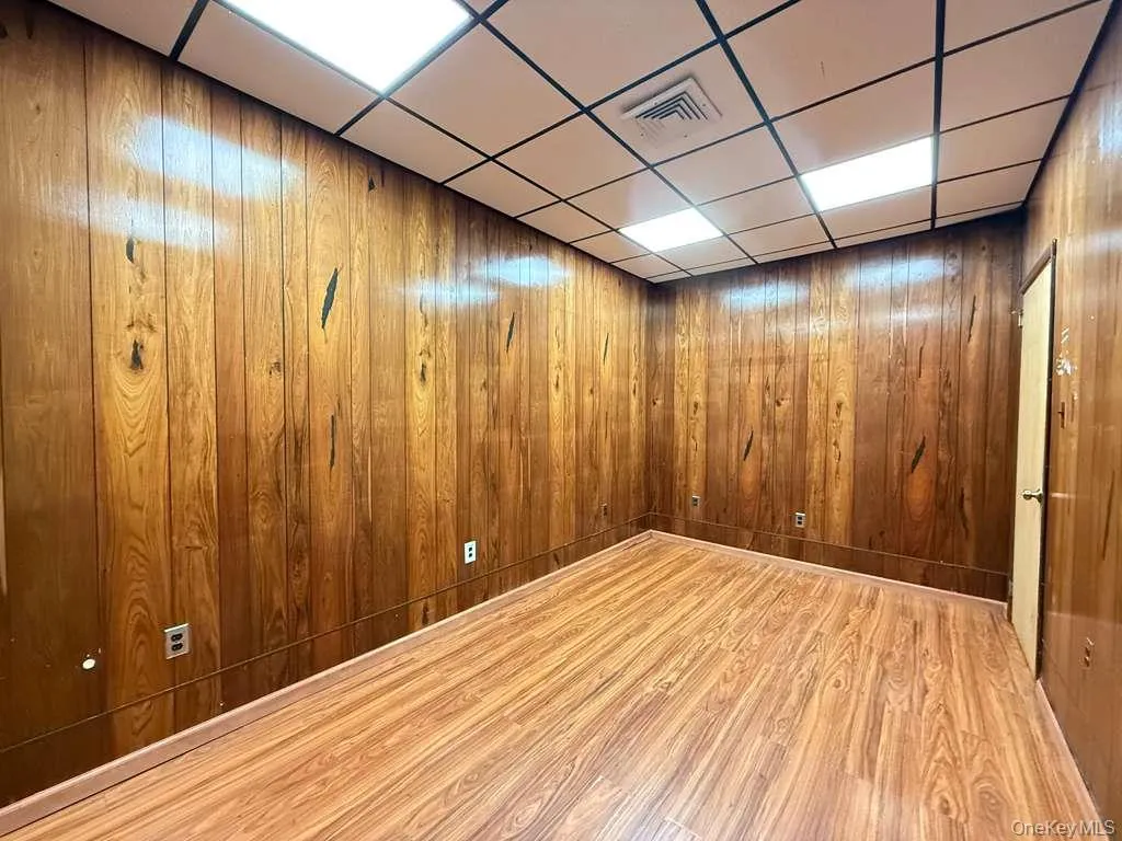 Spare room with wood finished floors, wooden walls, a paneled ceiling, and elevator Spare room with wood finished floors, wooden walls, a paneled ceiling, and elevator