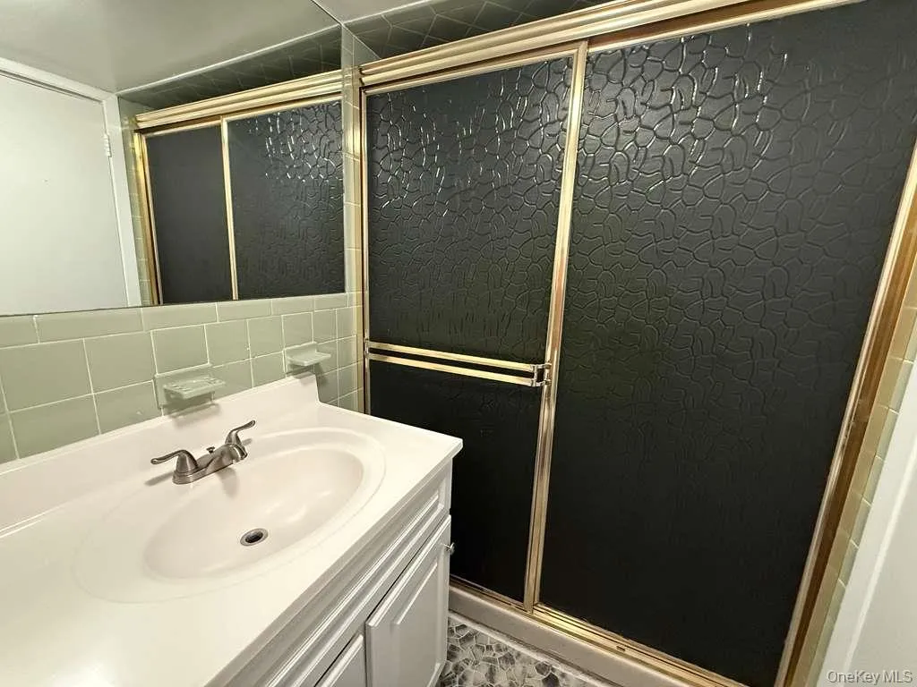 Full bathroom featuring tile walls, vanity, and a stall shower Full bathroom featuring tile walls, vanity, and a stall shower