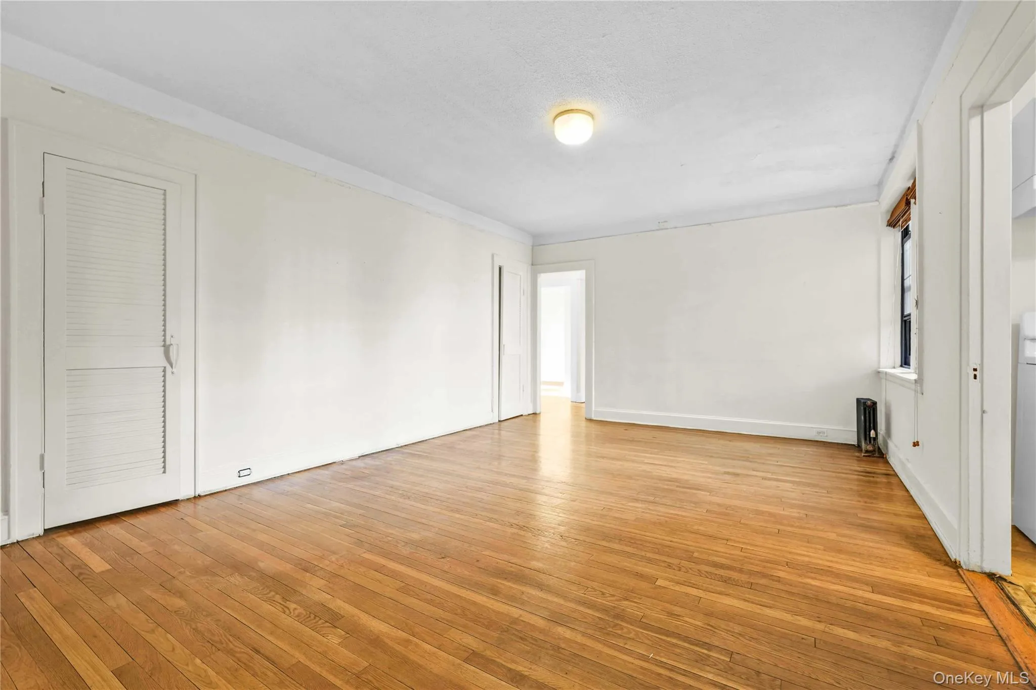 Unfurnished room with light wood-type flooring, radiator, and a textured ceiling Unfurnished room with light wood-type flooring, radiator, and a textured ceiling