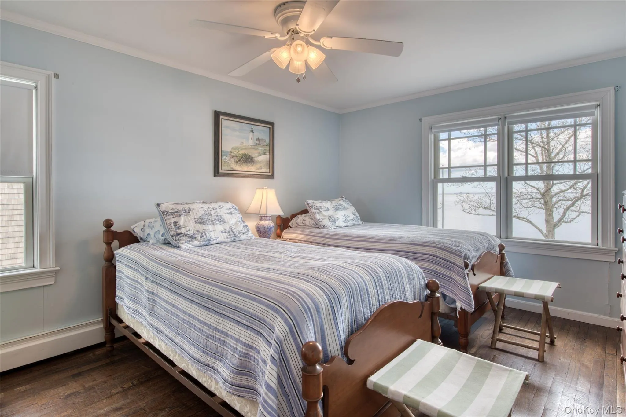 Bedroom with multiple windows, dark wood-style floors, crown molding, a ceiling fan, and baseboard heating unit Bedroom with multiple windows, dark wood-style floors, crown molding, a ceiling fan, and baseboard heating unit