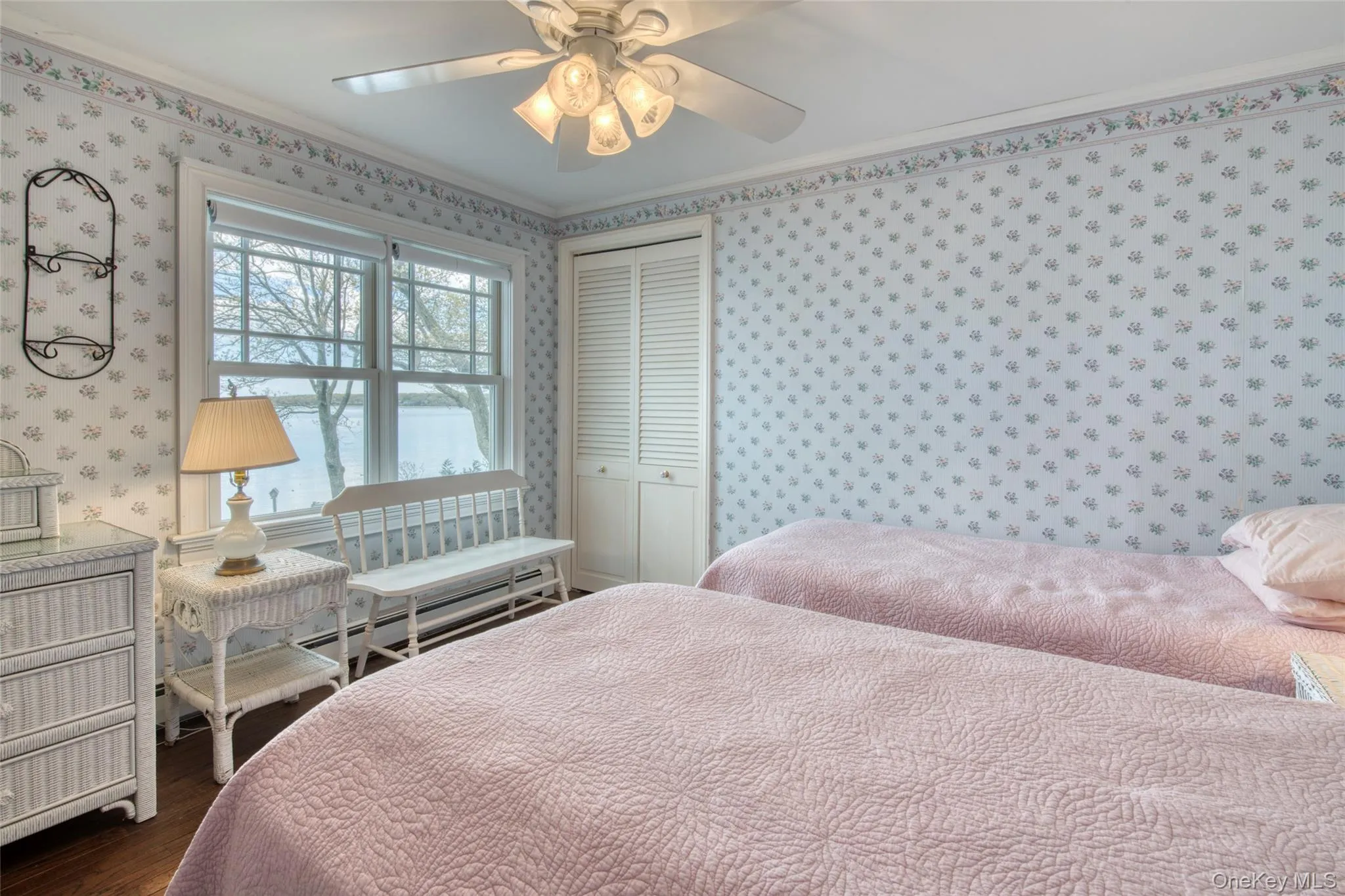 Bedroom with a closet, dark wood-type flooring, a ceiling fan, and wallpapered walls Bedroom with a closet, dark wood-type flooring, a ceiling fan, and wallpapered walls