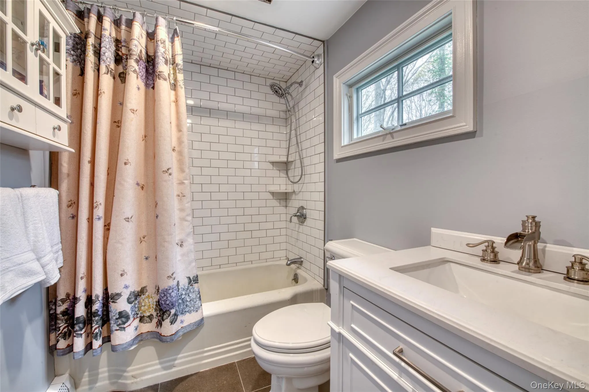 Secondary Full bath with shower / bath combo with shower curtain, vanity, dark tile patterned floors, and a baseboard radiator Secondary Full bath with shower / bath combo with shower curtain, vanity, dark tile patterned floors, and a baseboard radiator