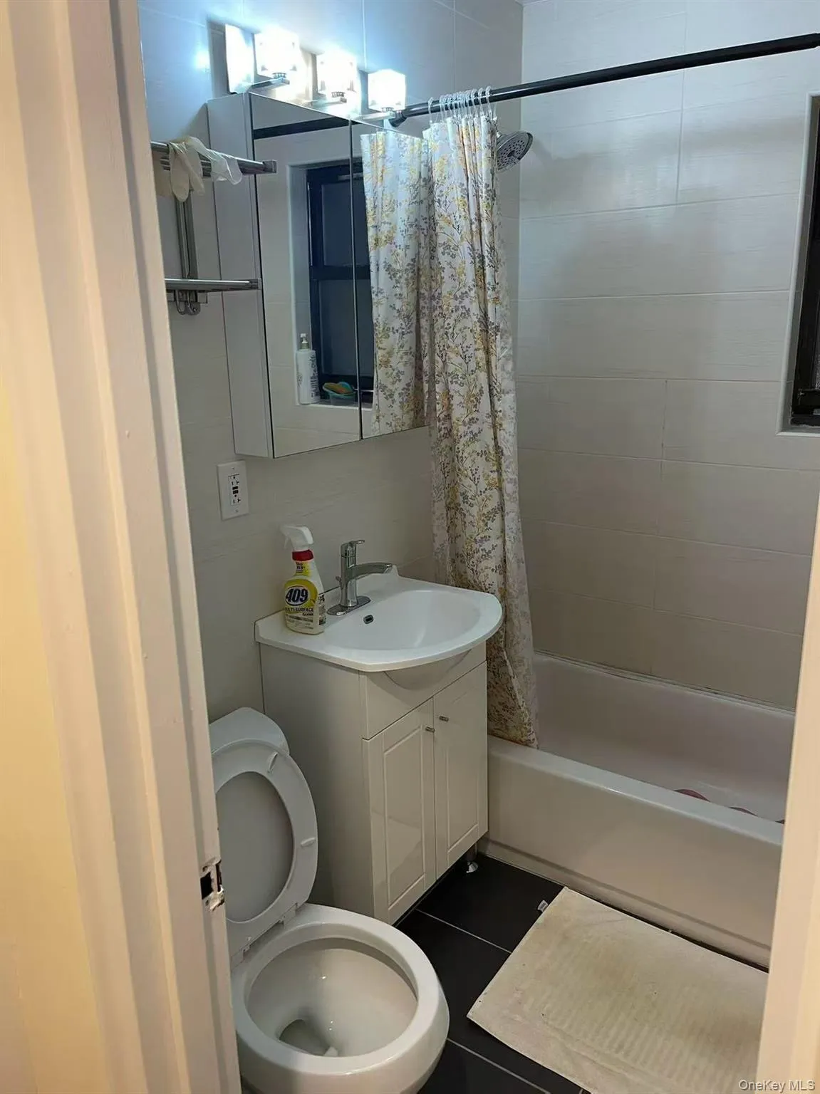 Full bathroom with vanity, shower / bathtub combination with curtain, and dark tile patterned flooring Full bathroom with vanity, shower / bathtub combination with curtain, and dark tile patterned flooring